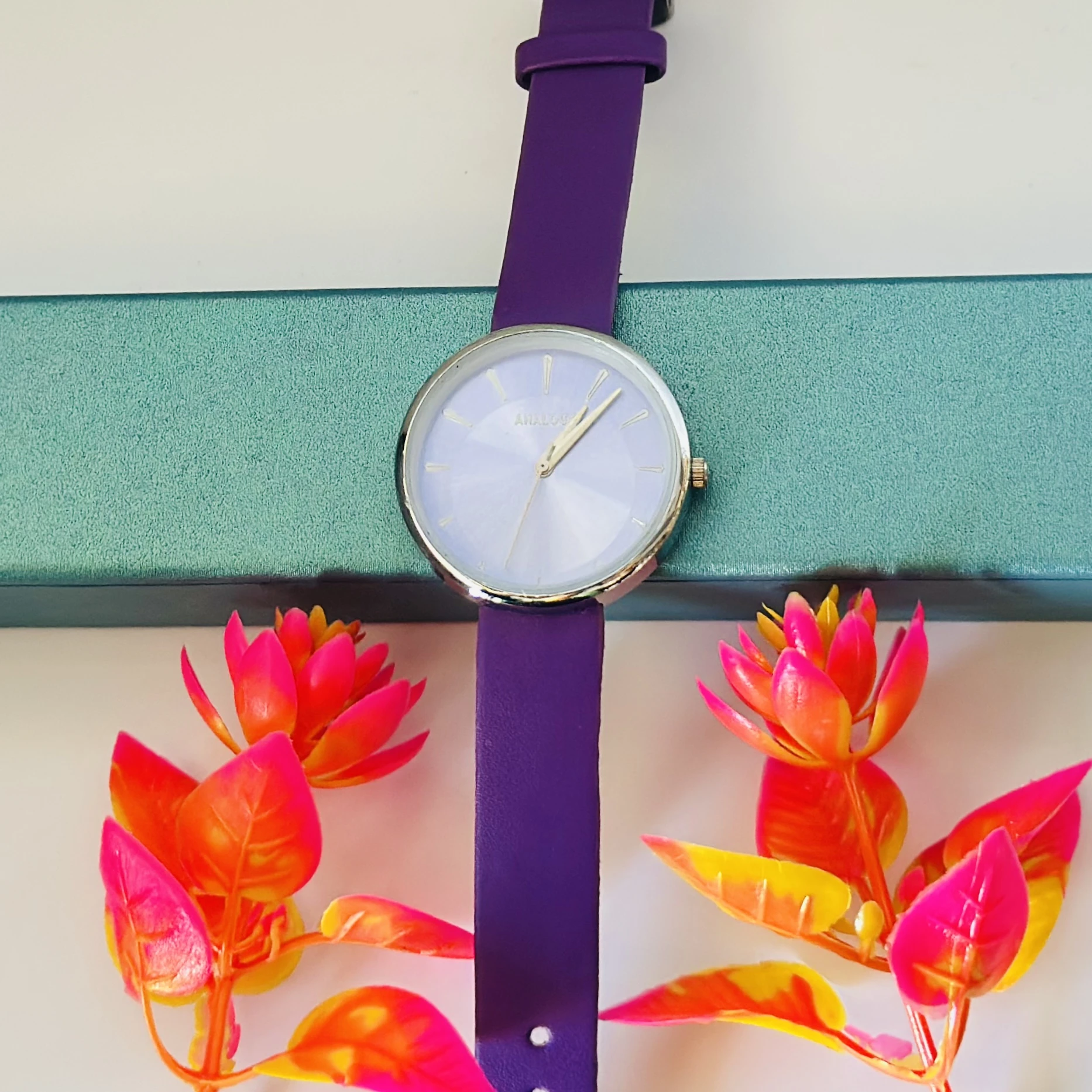 purple analog watch with a black leather strap.