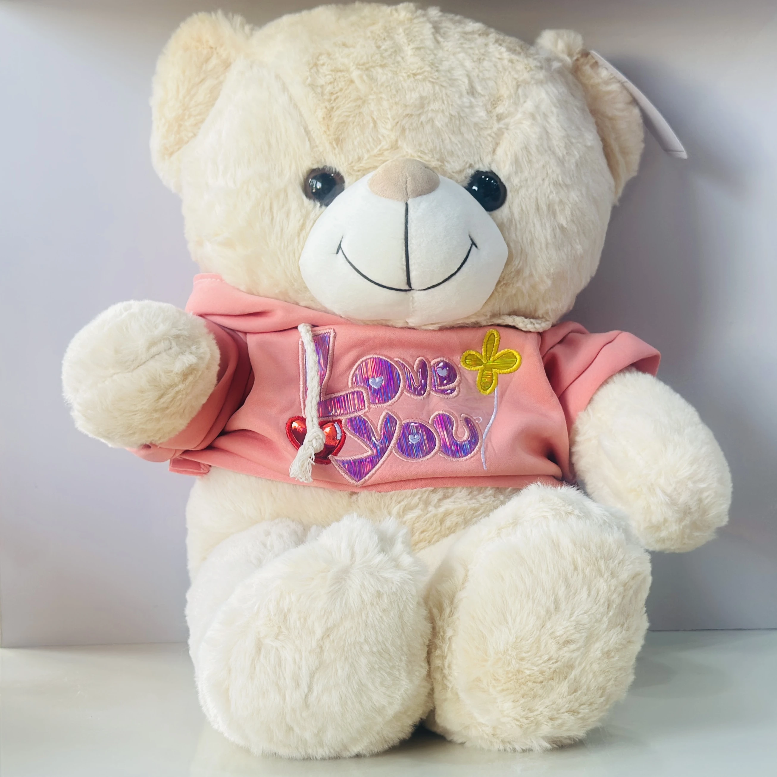 soft plush teddy bear toy wearing a pink hoodie with "I Love You" text.