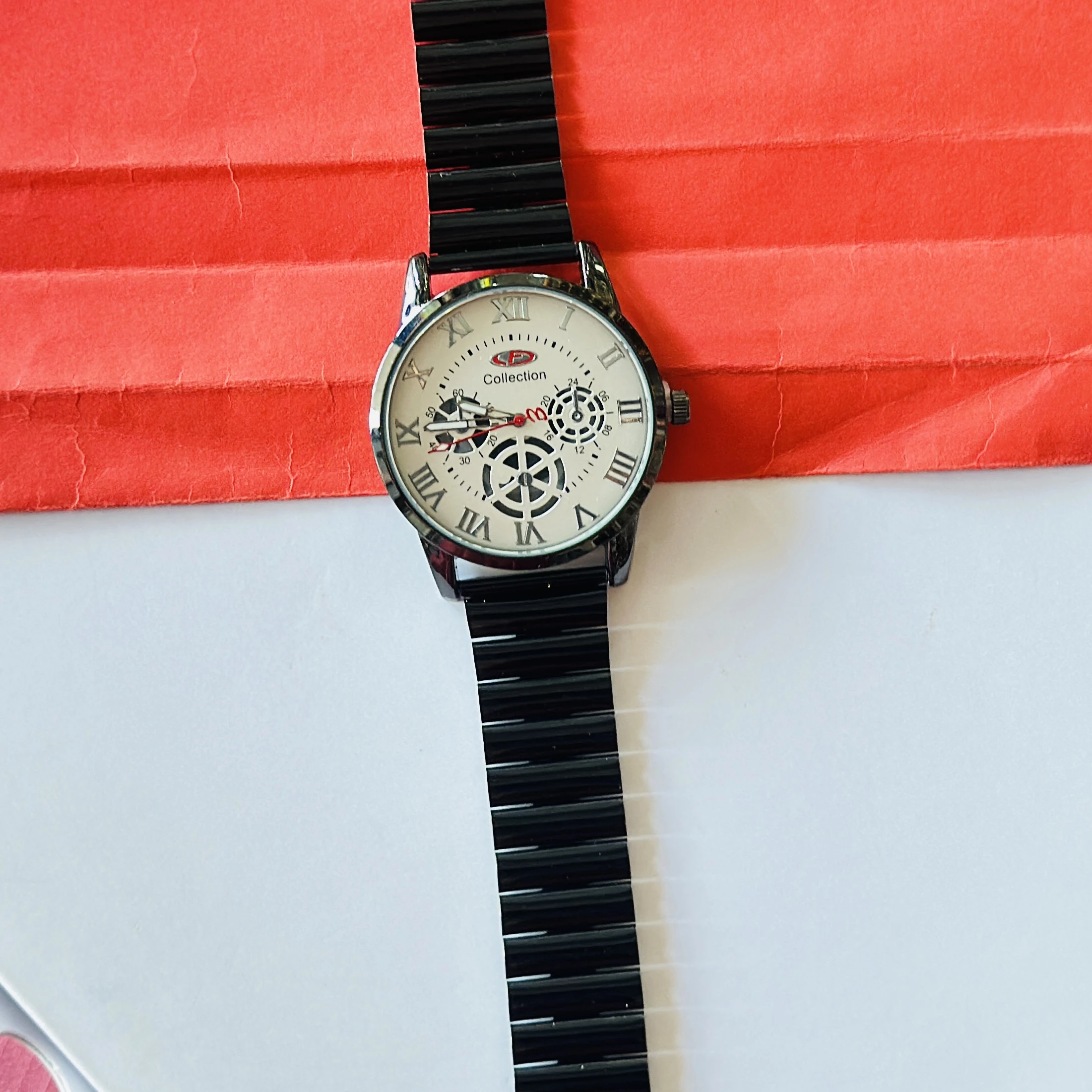 Black metal analog wristwatch with a white dial and roman numeral markers.