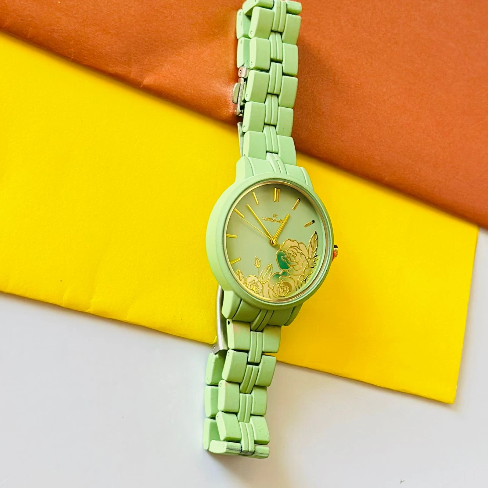 light green women's analog watch with a floral print on the dial and a link bracelet.