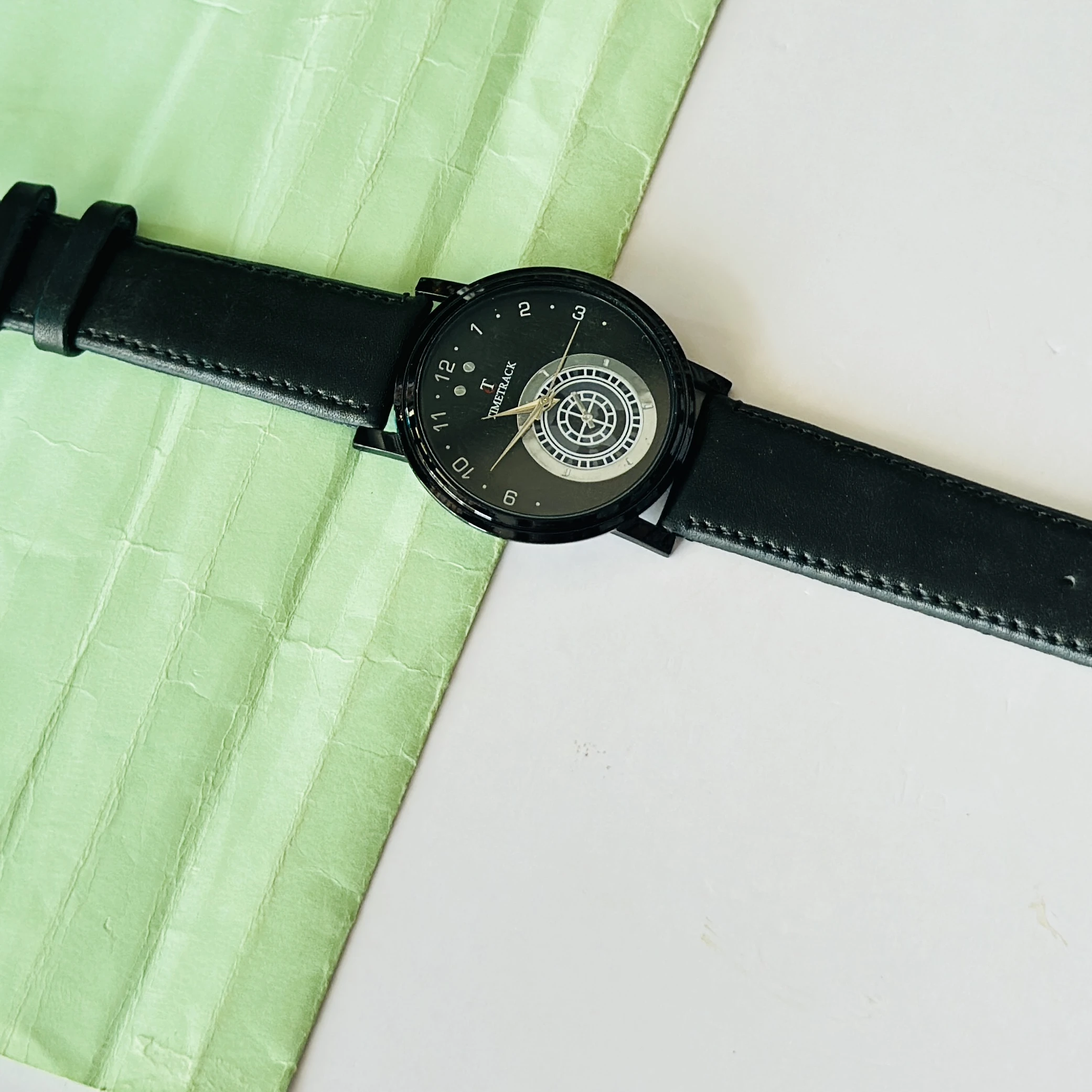 Timetrack quartz analog watch with a black leather strap and a distinctive patterned dial
