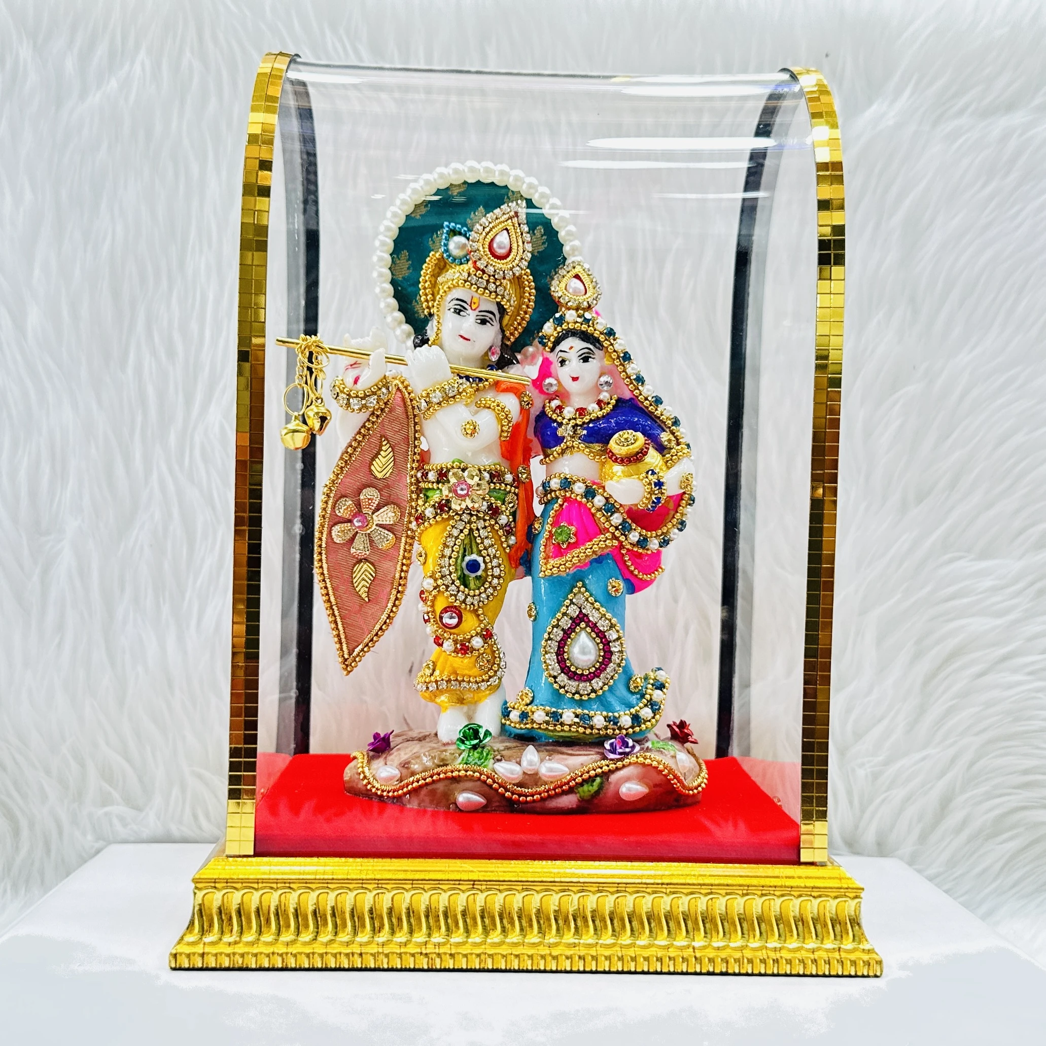 Radha Krishna statue enclosed in a protective glass dome.