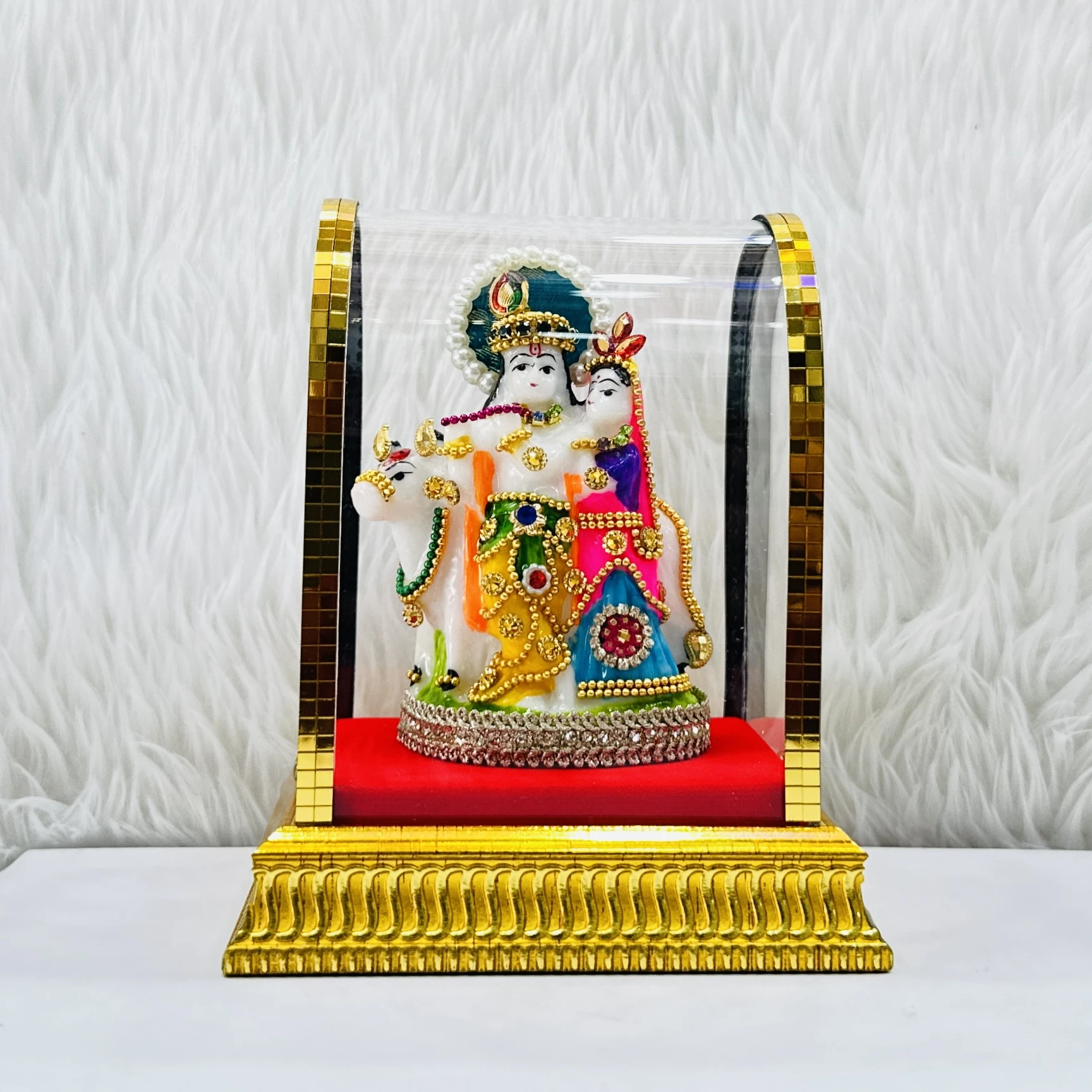 Radha Krishna statue enclosed in a protective glass dome.