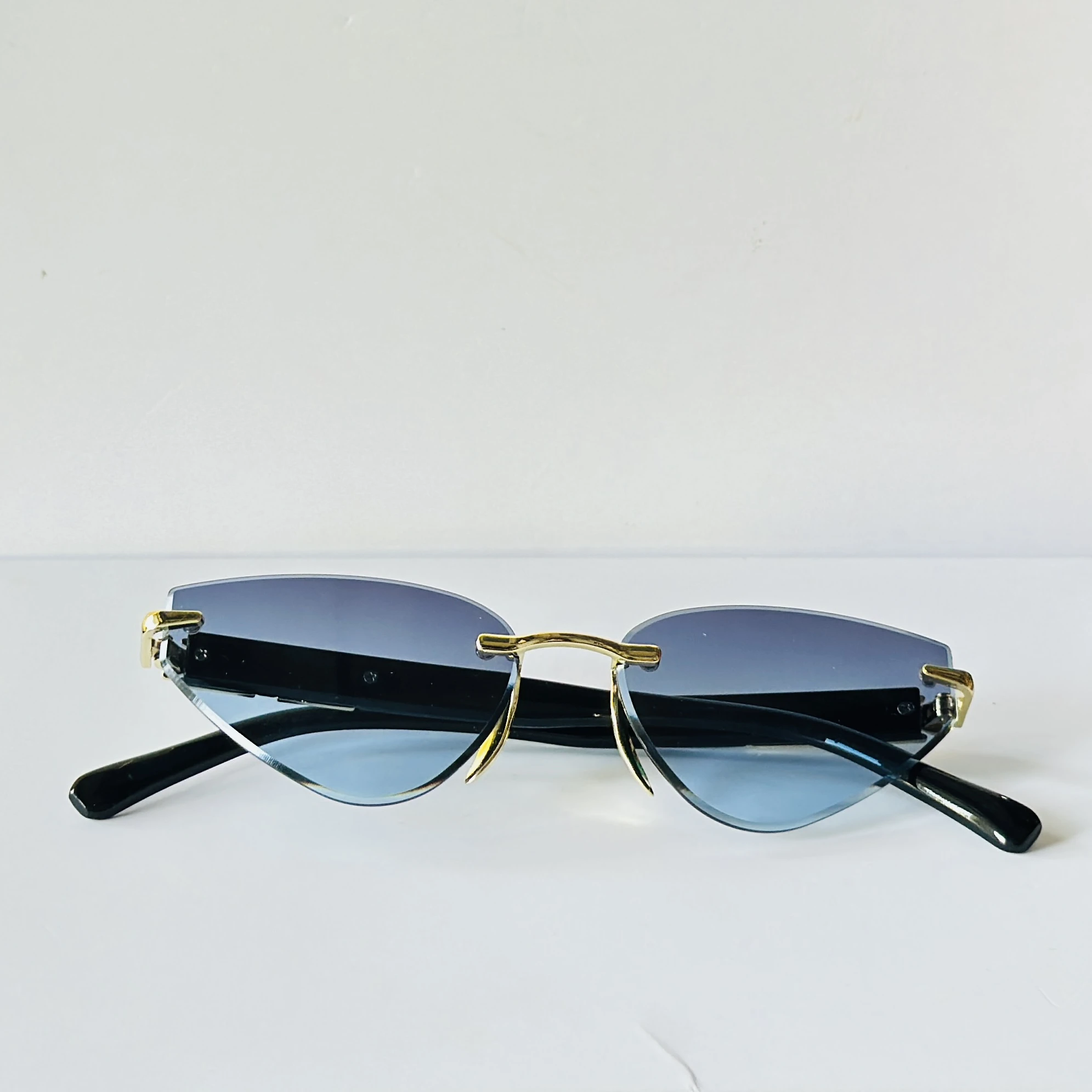 Rimless cat-eye sunglasses feature golden metal frame