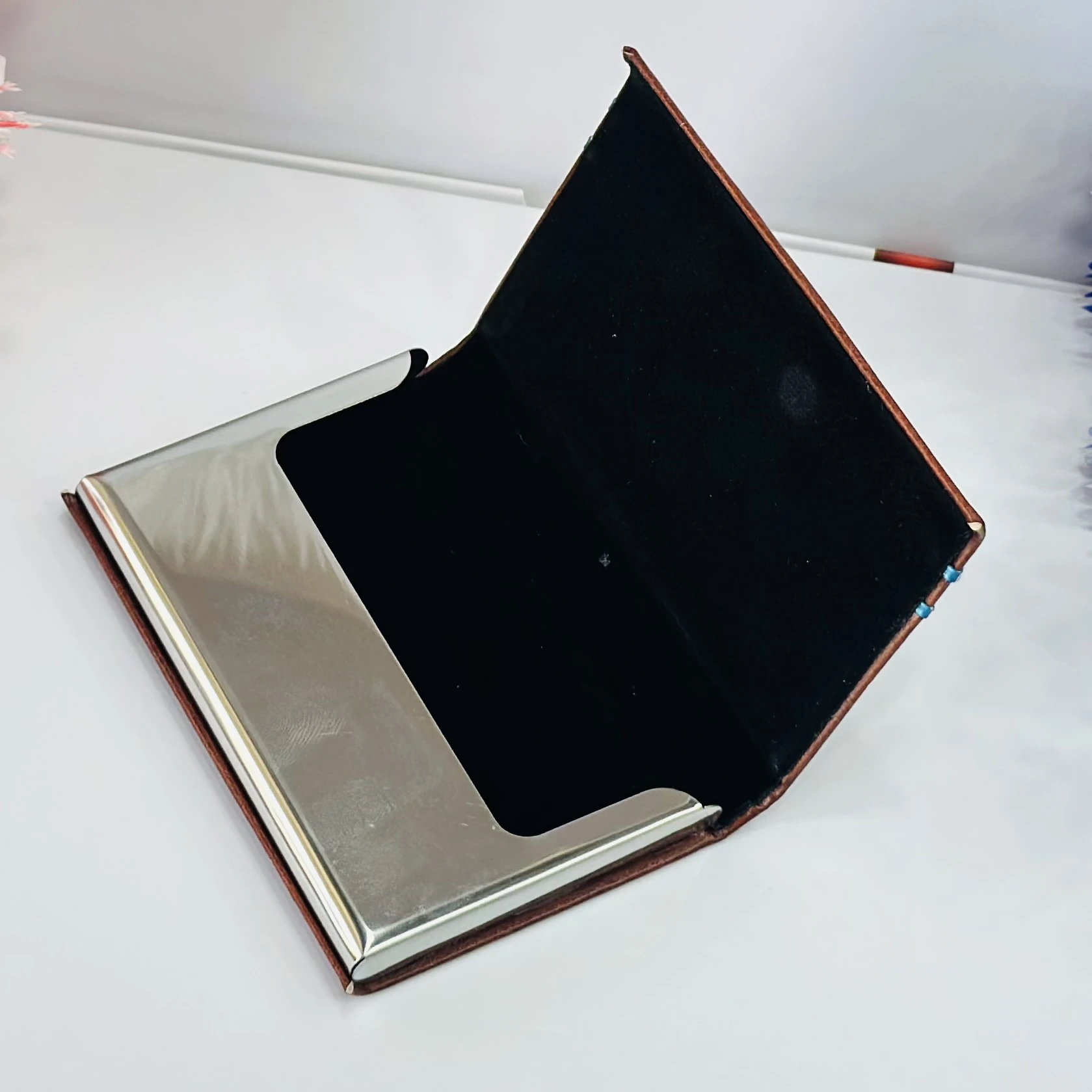 brown leather business card holder with blue metal accents.
