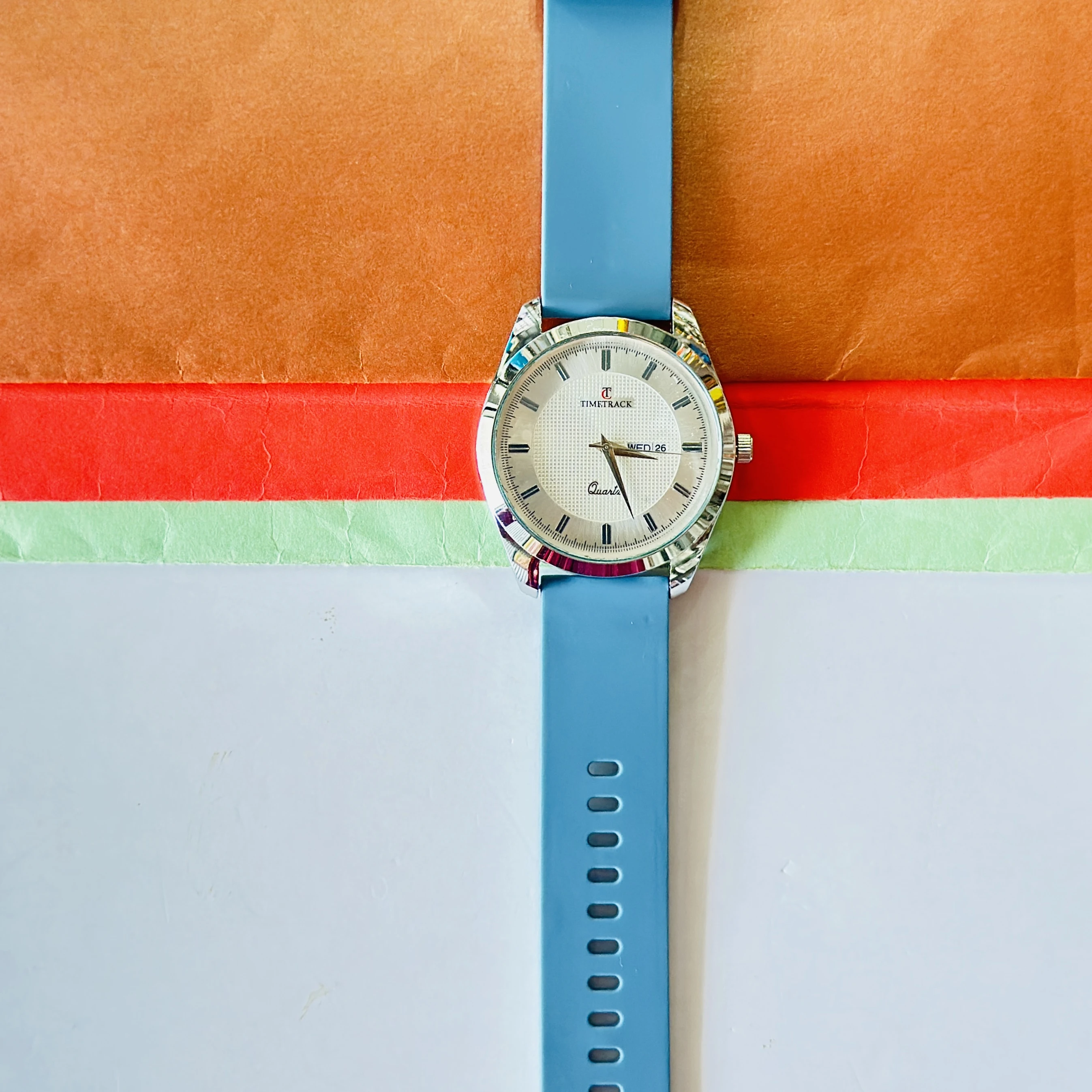 Timetrack quartz analog watch with a white textured dial and a blue silicone strap.
