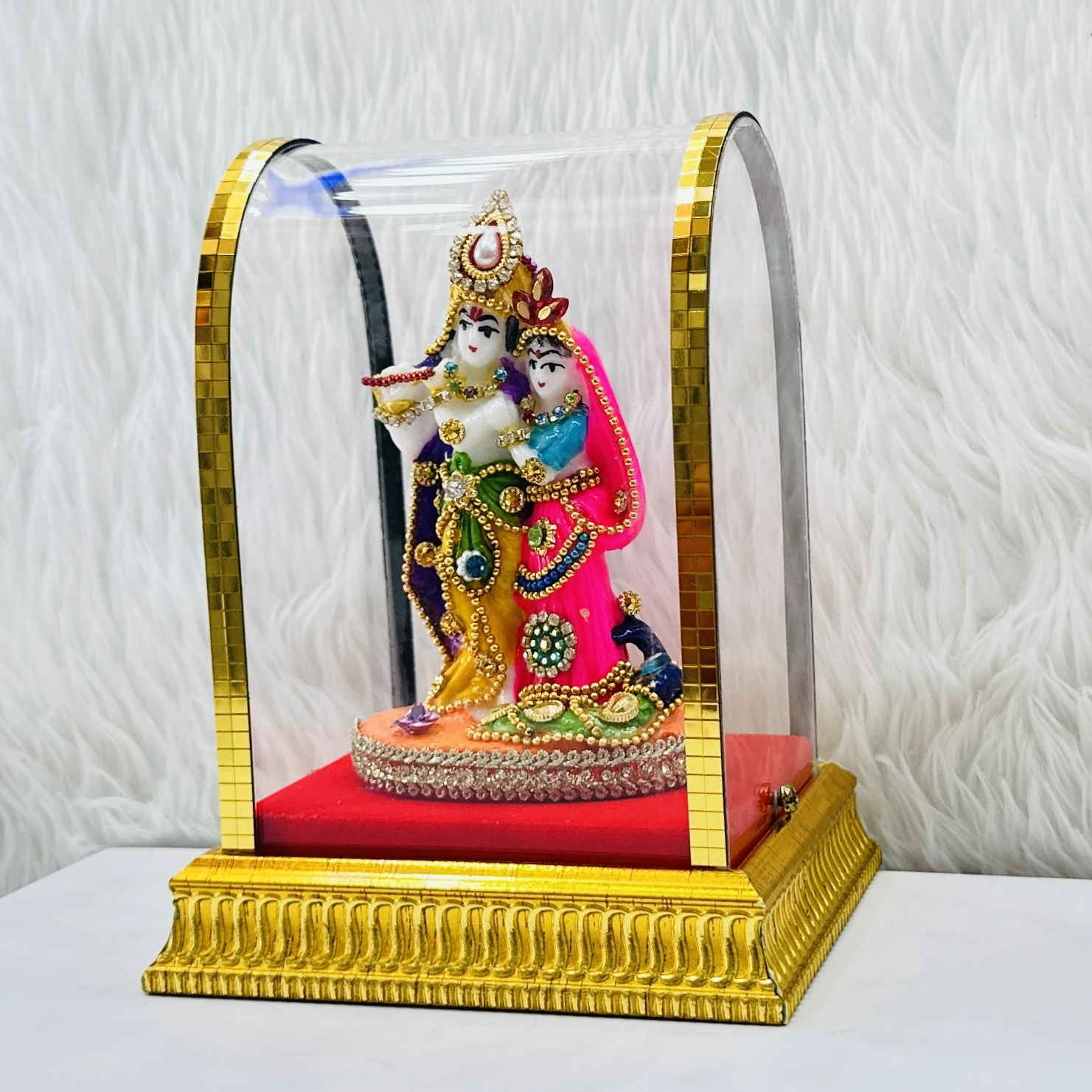Radha Krishna statue enclosed in a protective glass case.