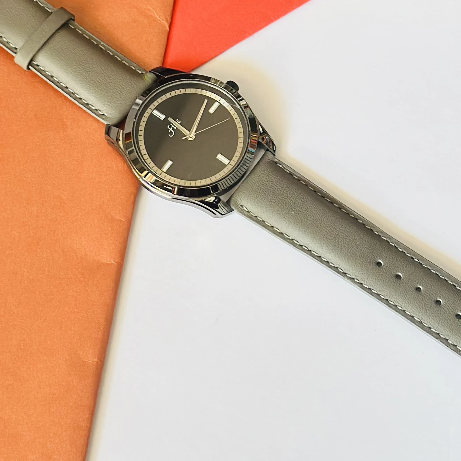 watch with a gray leather strap and a black dial.