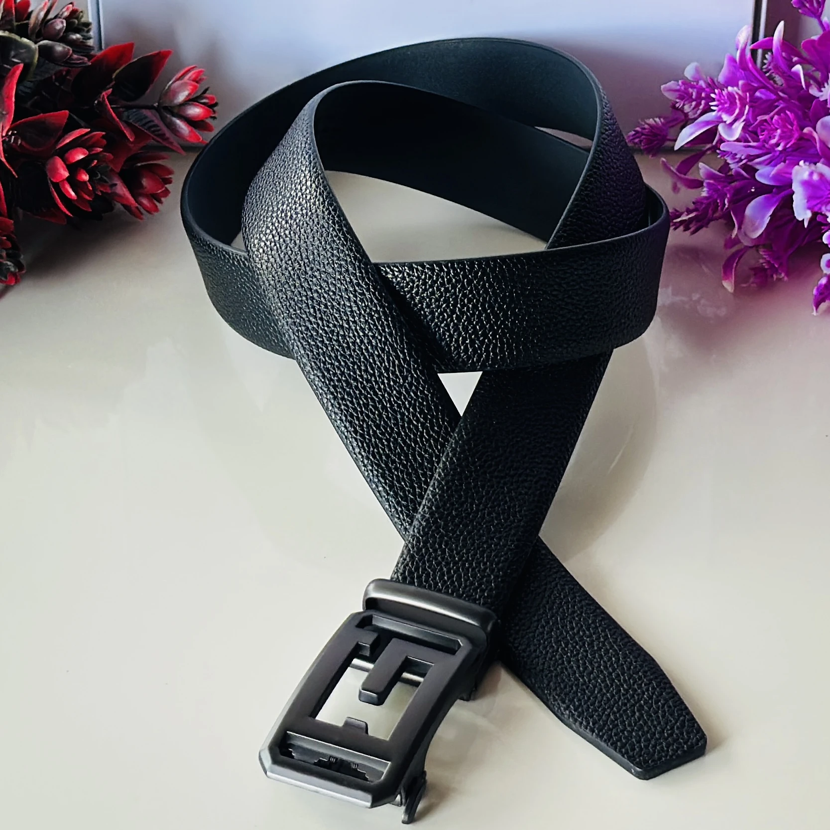 Men’s black faux leather automatic ratcheting belt with a 'G' shaped buckle.
