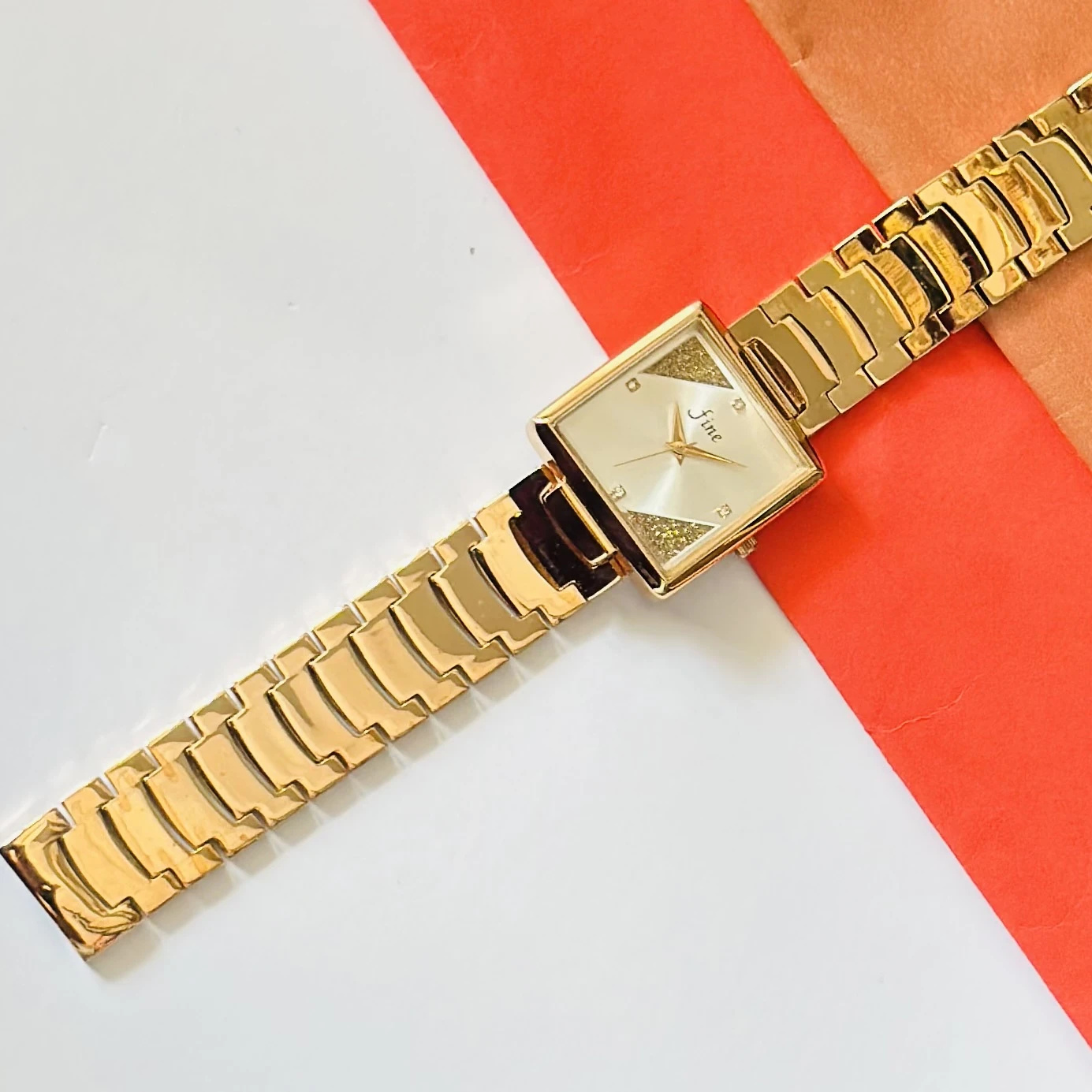 Gold -tone analog watch with a square dial and a metal strap.