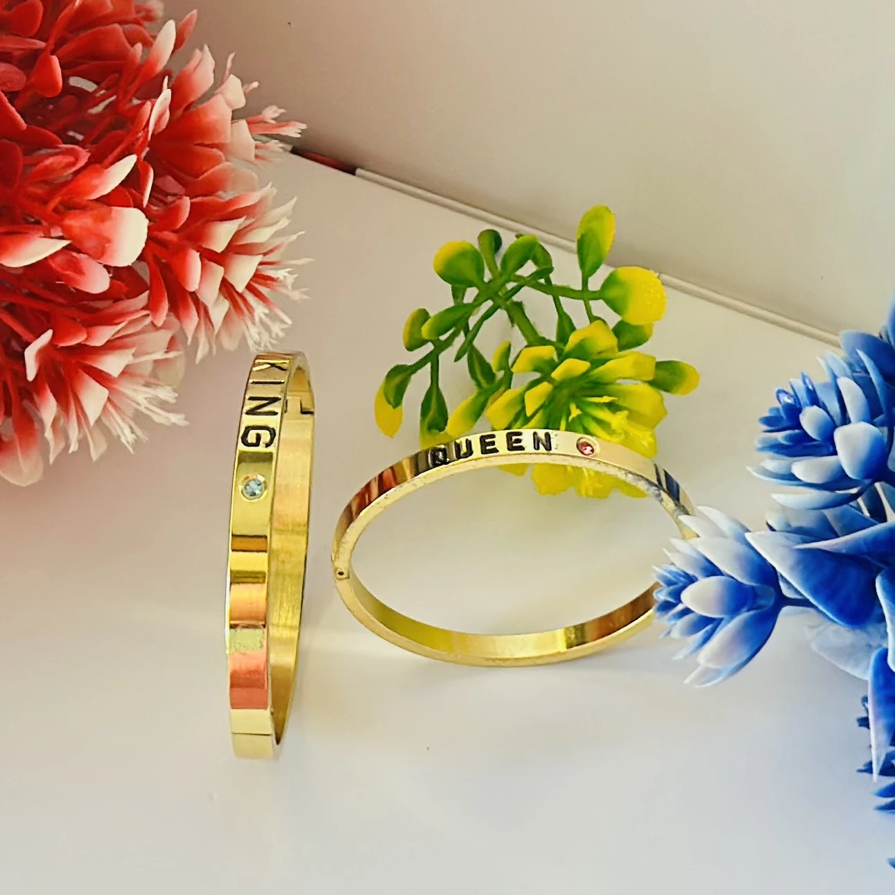 Gold plated "Queen" cuff bracelet with a pink stone accent.