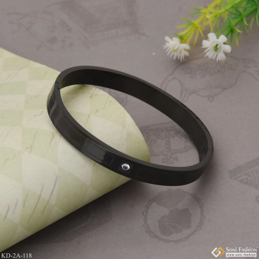 Black stainless steel kada bracelet with a single crystal accent.