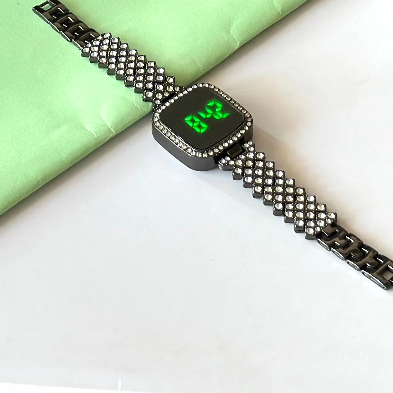 black-toned digital watch with an embellished rhinestone bracelet strap.