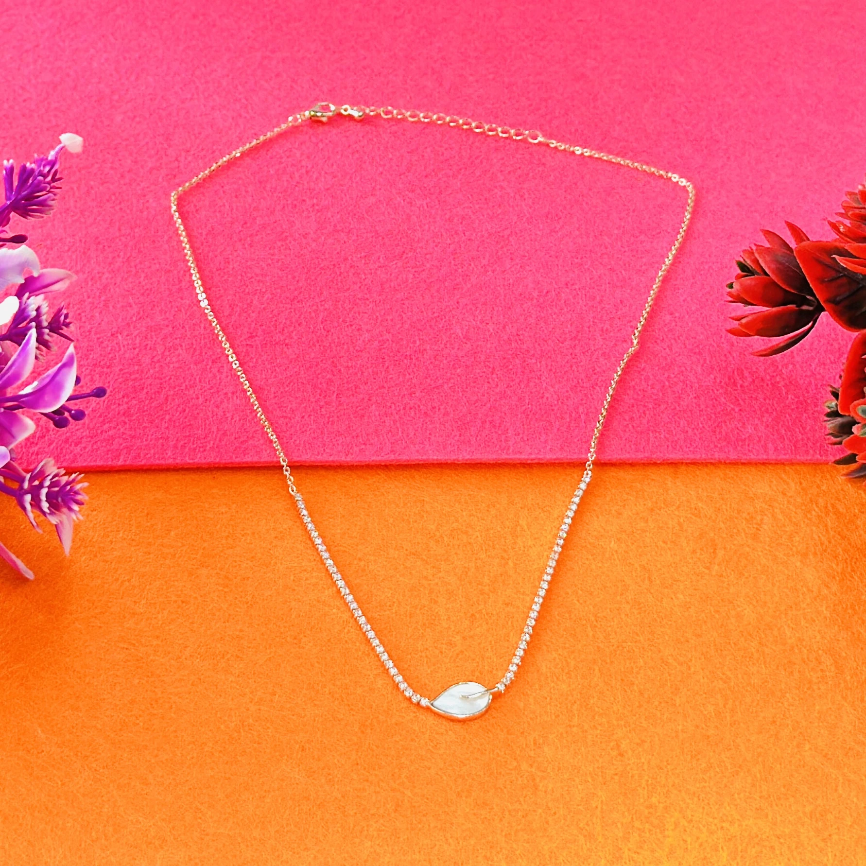 Gold plated chain necklace with a leaf-shaped white pendant.