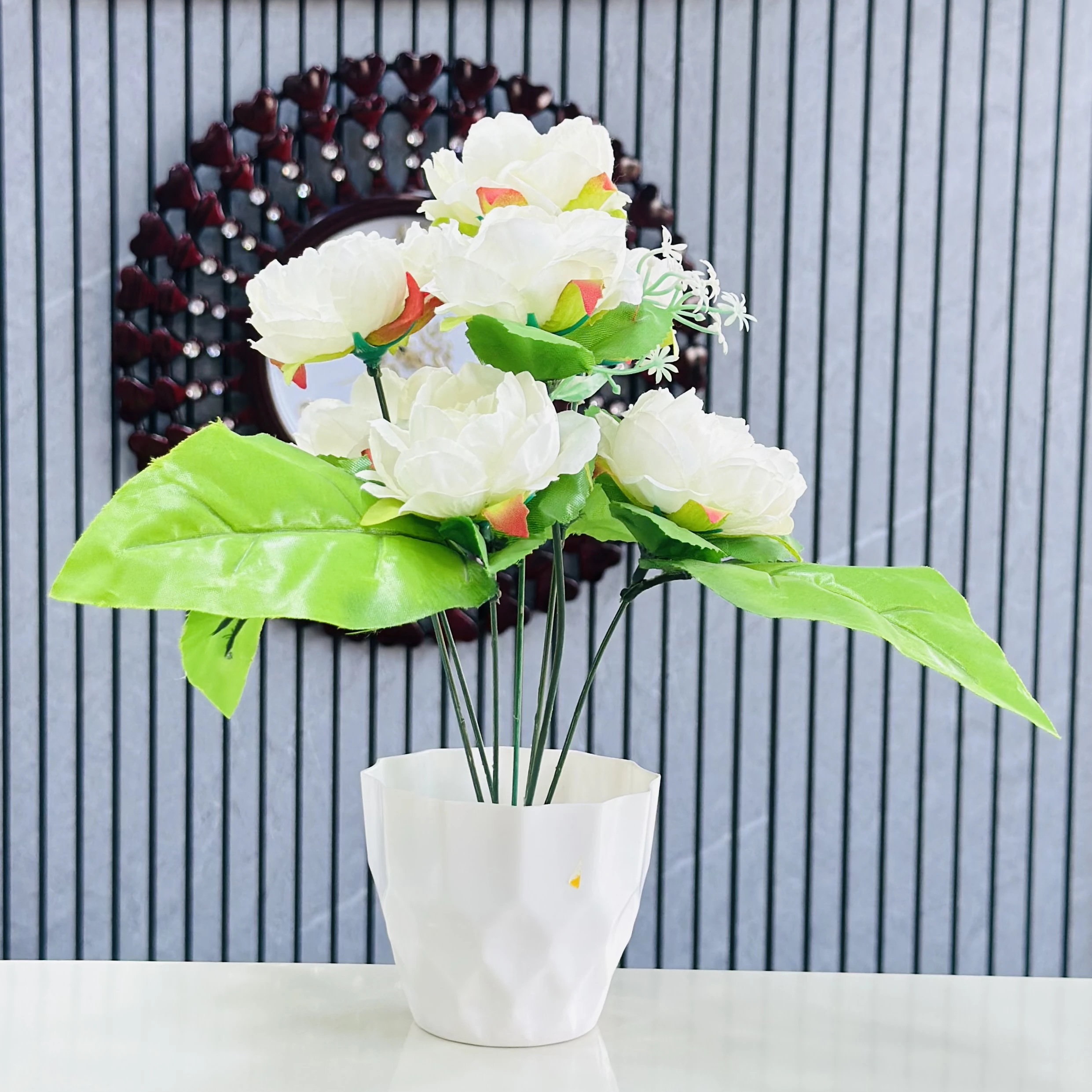 Lotus flower arrangement in a white geometric pot.