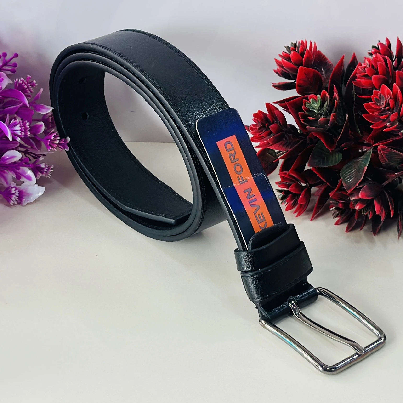 black belt with a silver-tone buckle and a "KEVIN FORD" label.