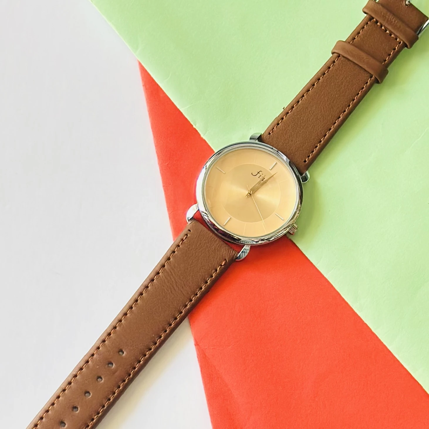 Analog wristwatch with a gold-tone case and a brown leather strap.