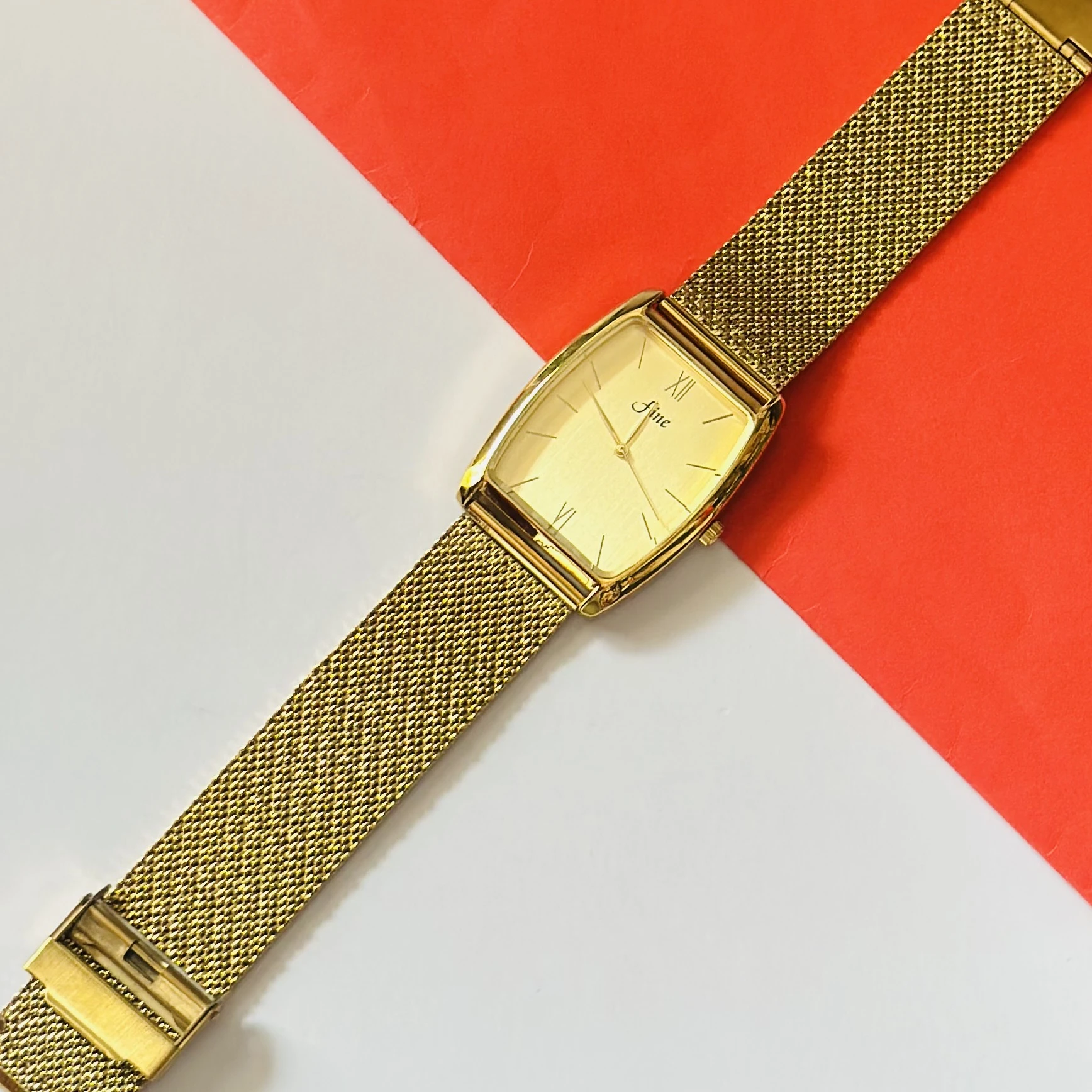 Gold -plated quartz analogue watch with a mesh strap.
