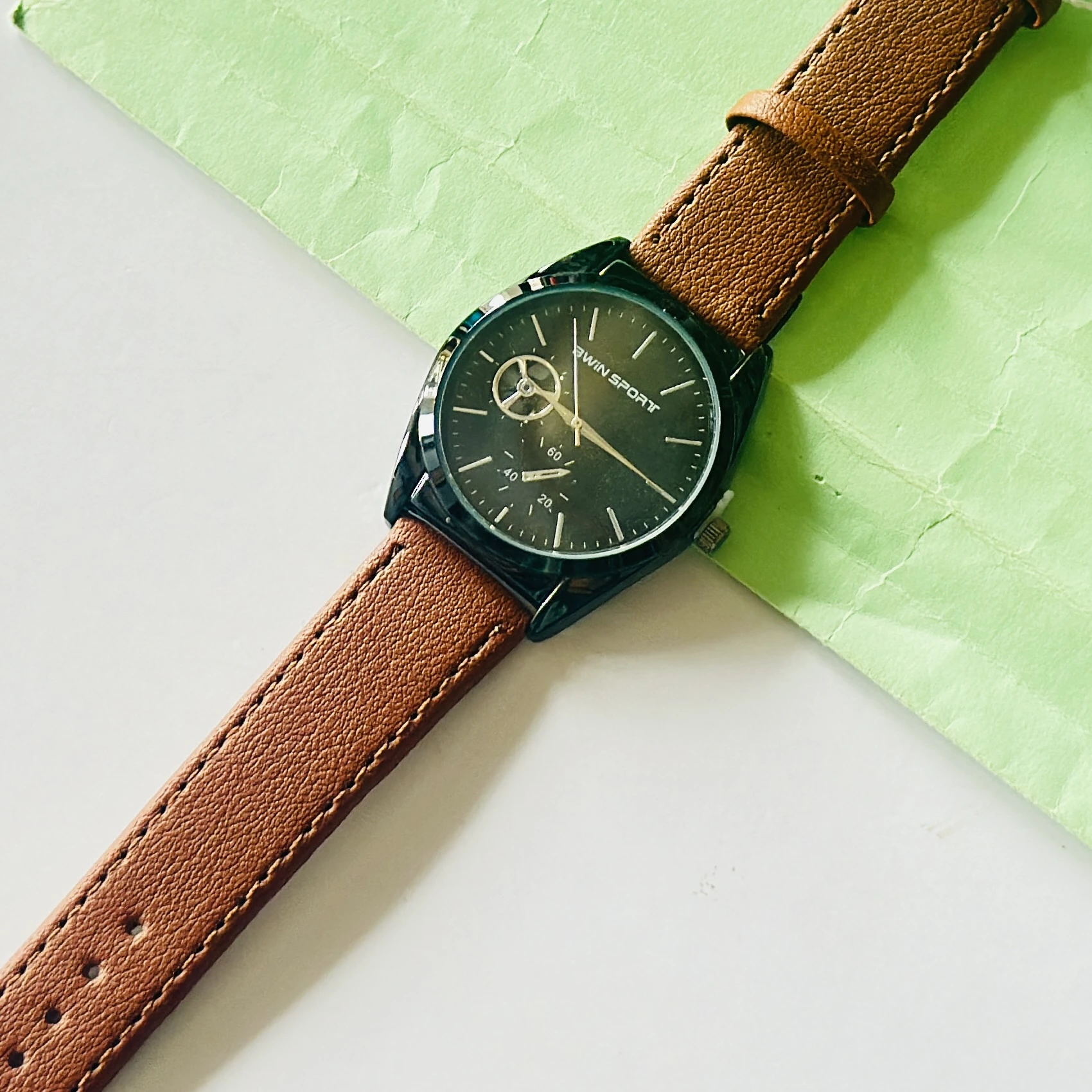 Carlington analog watch with a brown faux leather strap and a black dial.