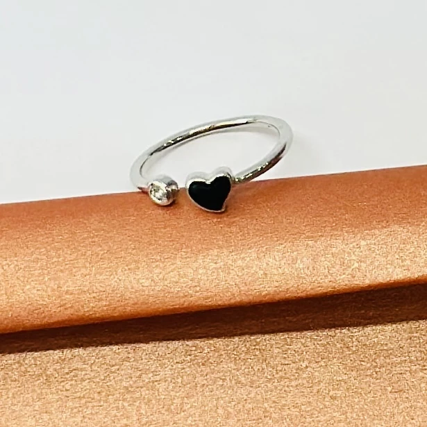 An adjustable silver-toned ring with a black heart and a clear stone accent.