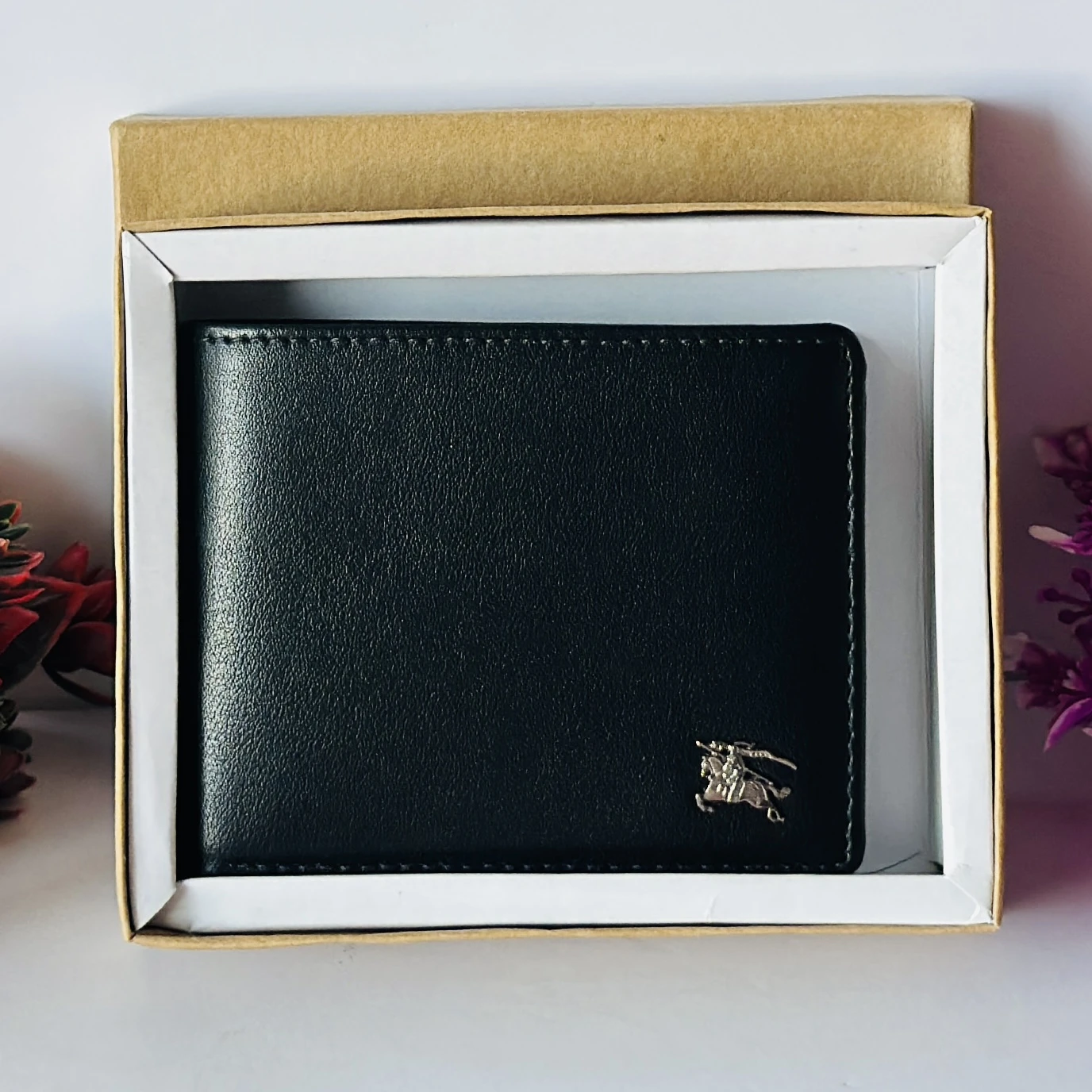 Black bifold leather wallet with a metal logo accent.