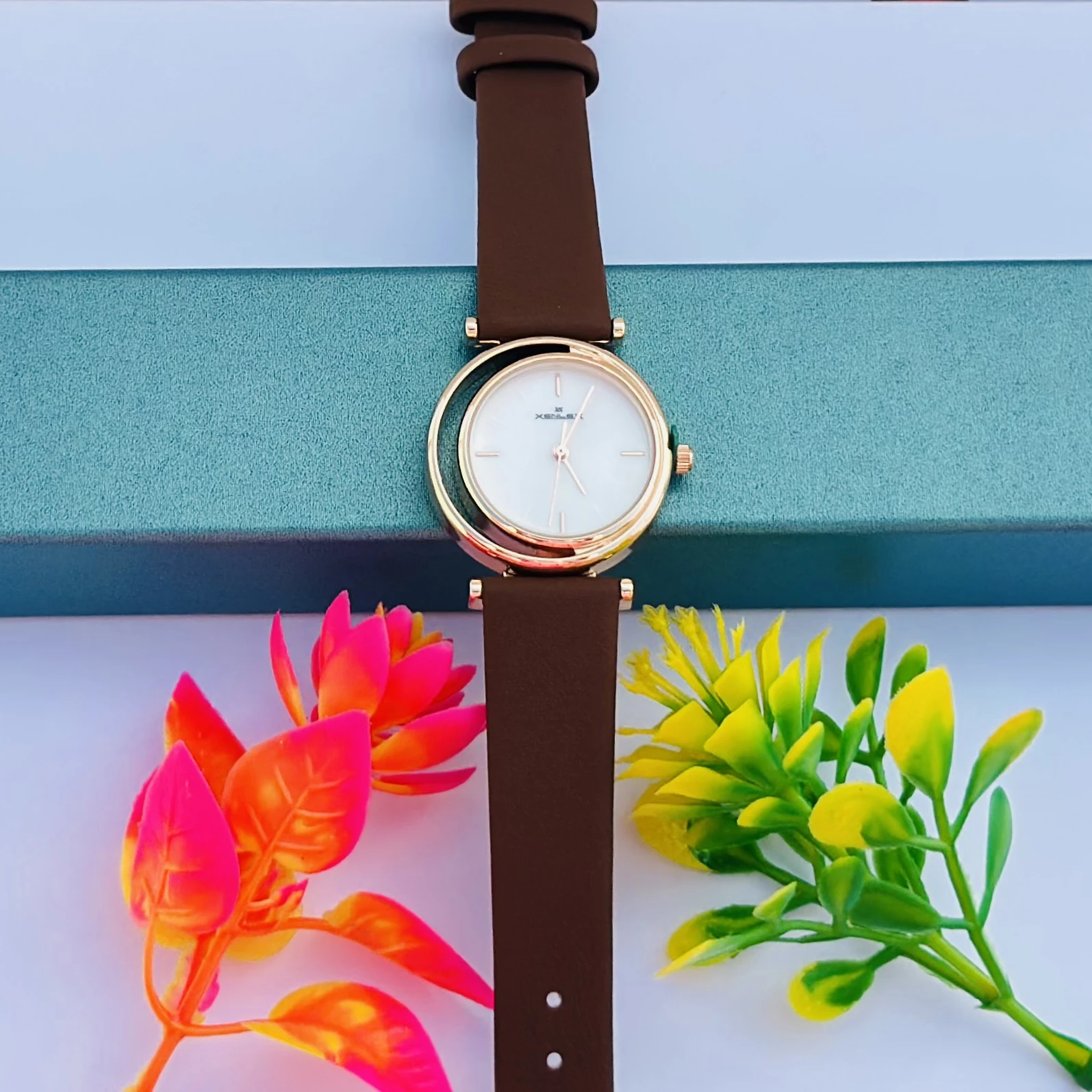 women's gold-toned analogue watch with a dark brown leather strap.