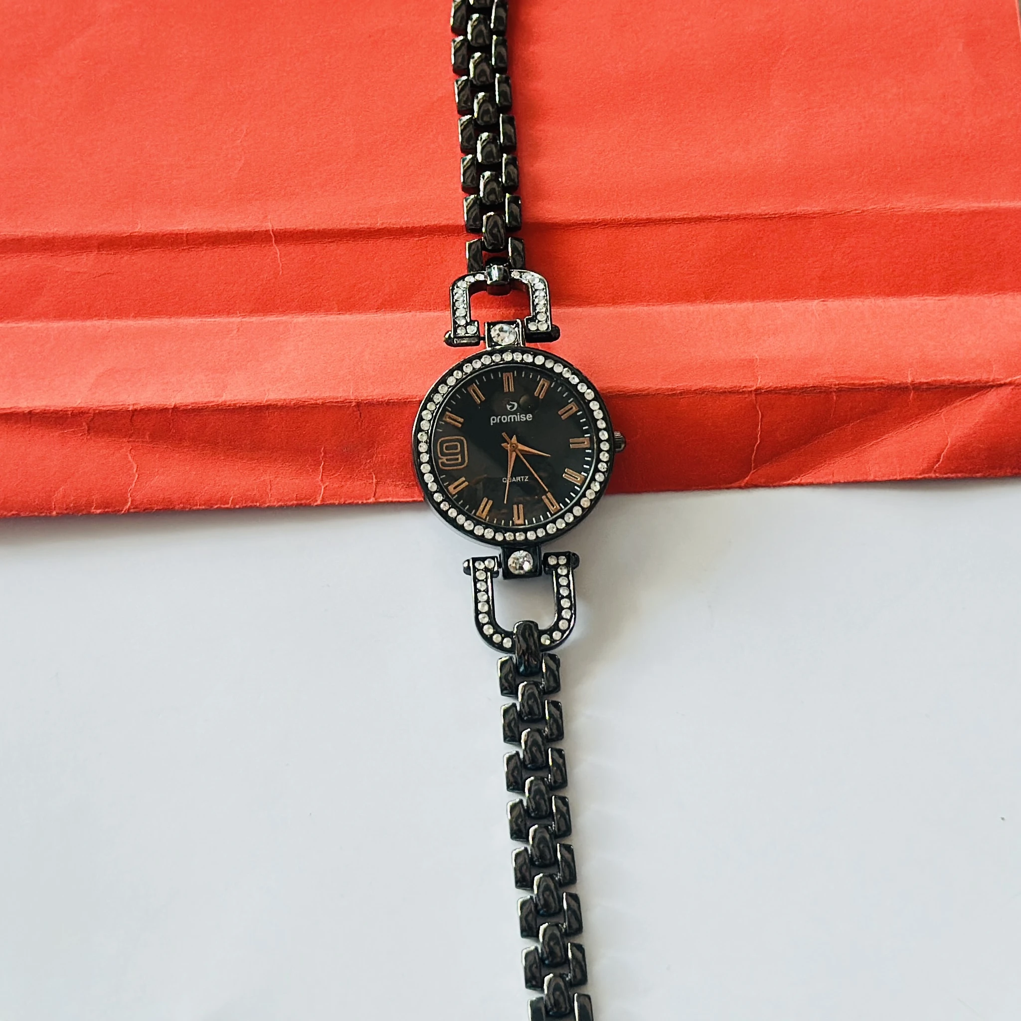 women's bracelet watch featuring a black dial and a diamond-studded bezel.