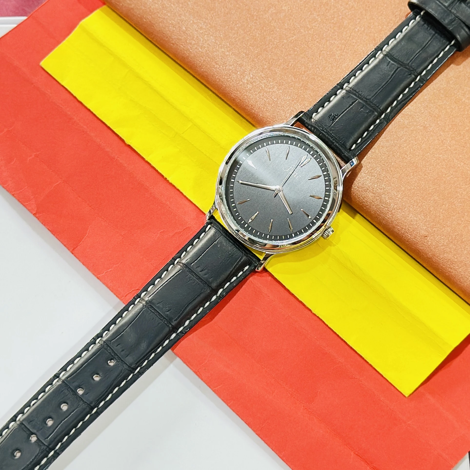 wrist watch featuring a black dial branded as "fine" and a black leather strap.