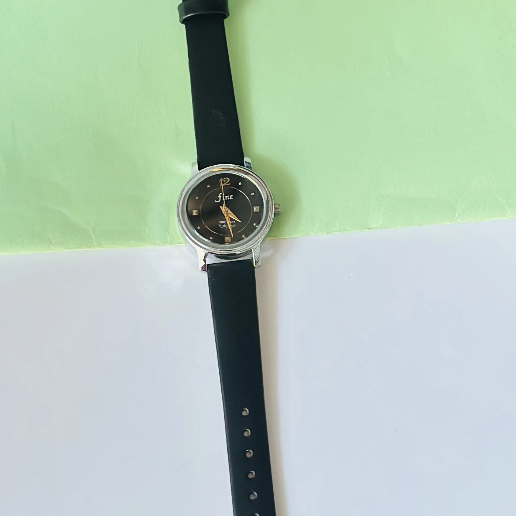 Black analog watch with a black strap.