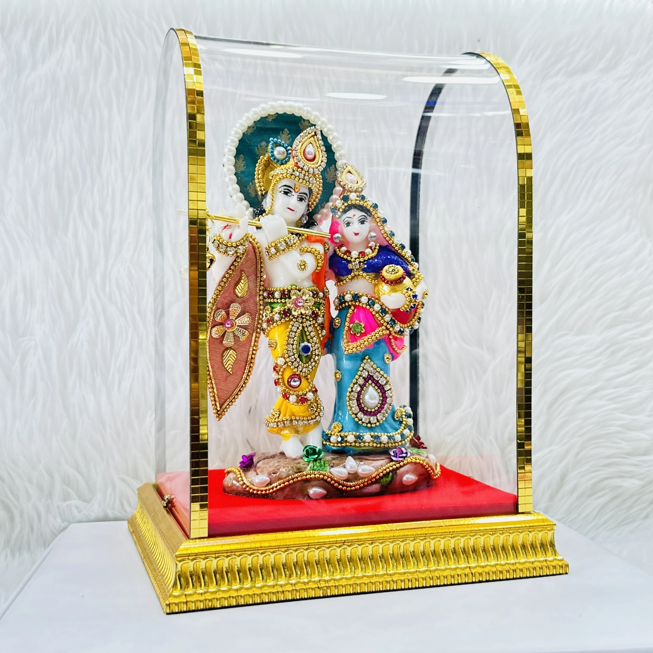 Radha Krishna statue enclosed in a protective glass dome.
