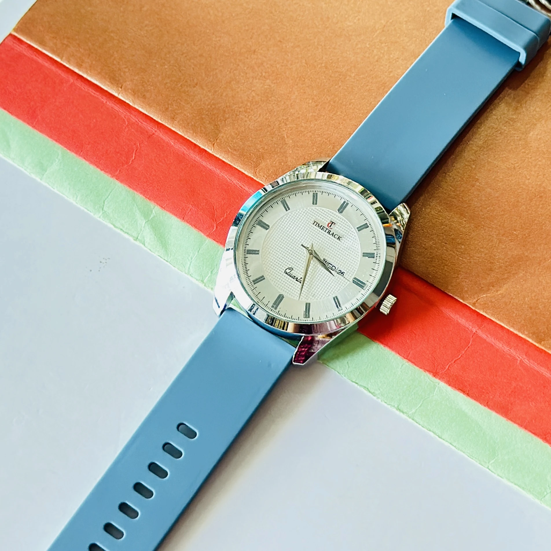 Timetrack quartz analog watch with a white textured dial and a blue silicone strap.