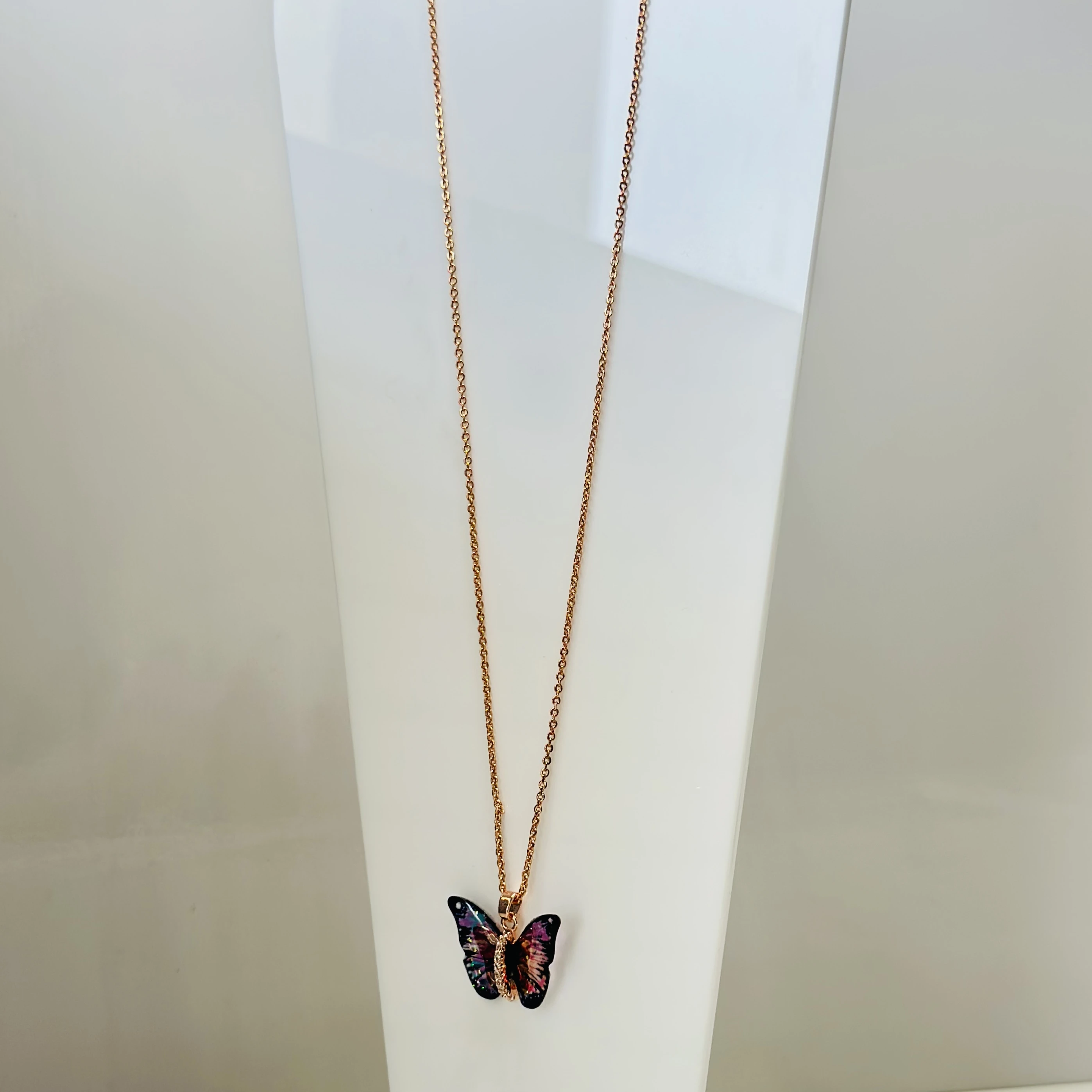 Rose gold-toned with a colorful butterfly pendant featuring a rhinestone accent