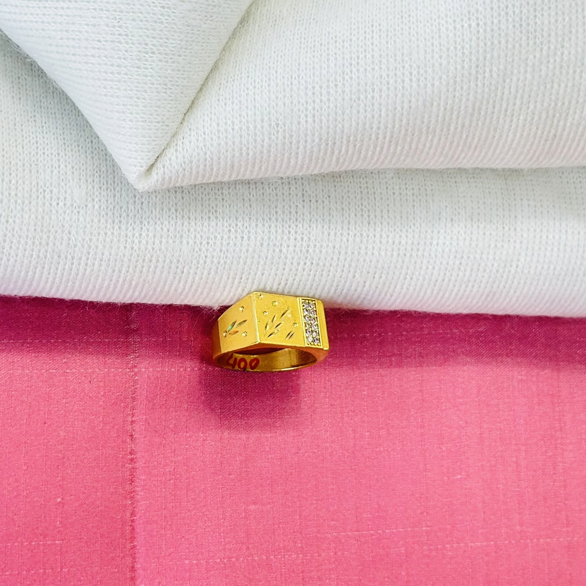 An engraved gold-toned men's ring with small white stones.