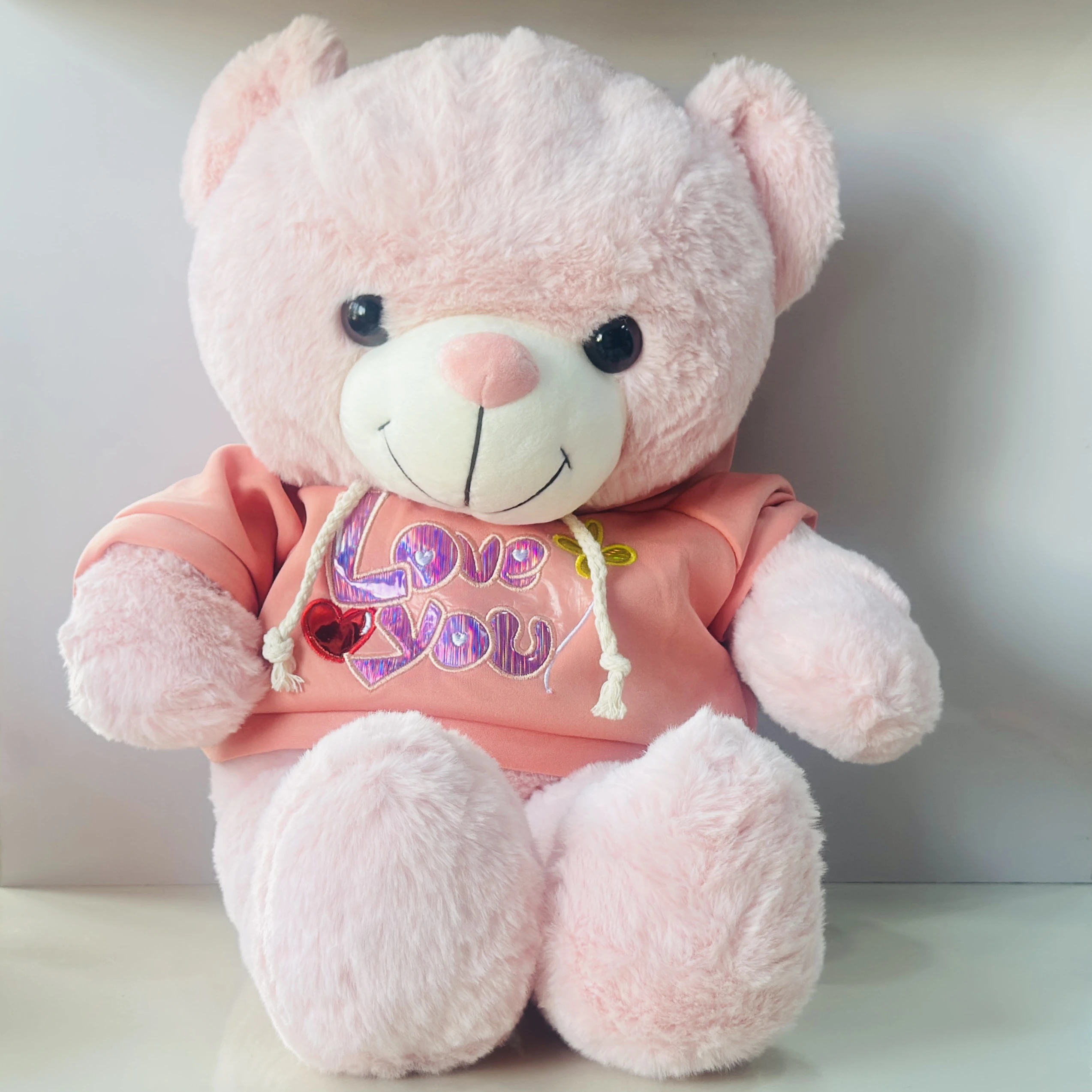 soft plush teddy bear toy wearing a pink hoodie with "I Love You" text.