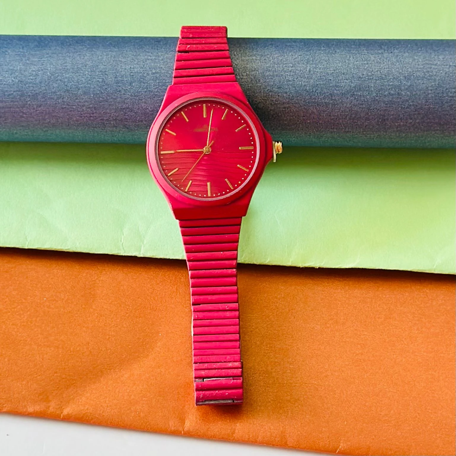 bright magenta or red analog watch with a matching link bracelet.