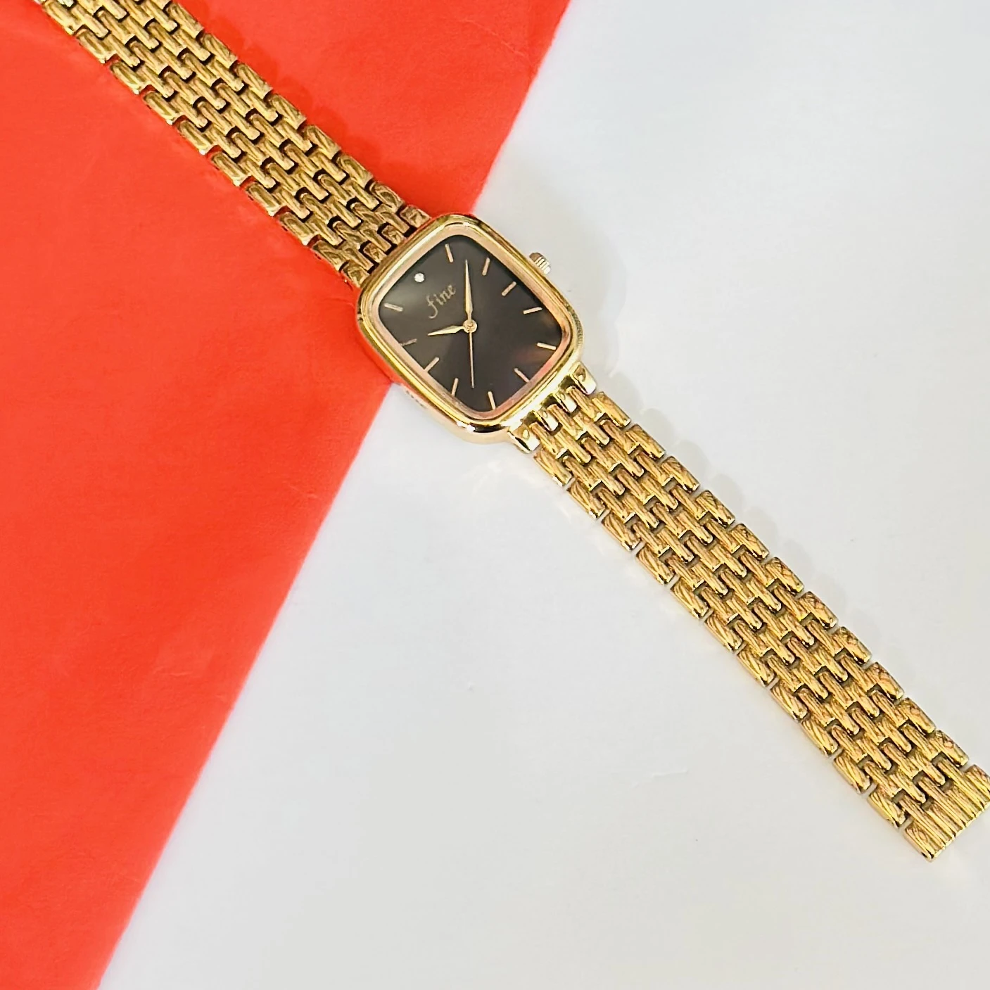 Gold tone analog watch with a square dial and a metal strap.