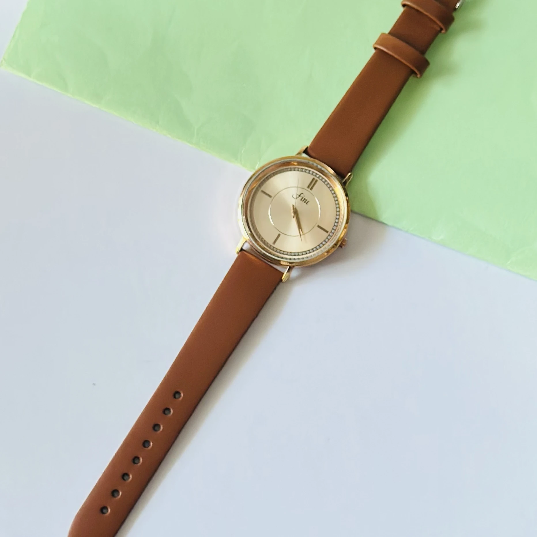 Gold tone analog wrist watch with a brown leather strap