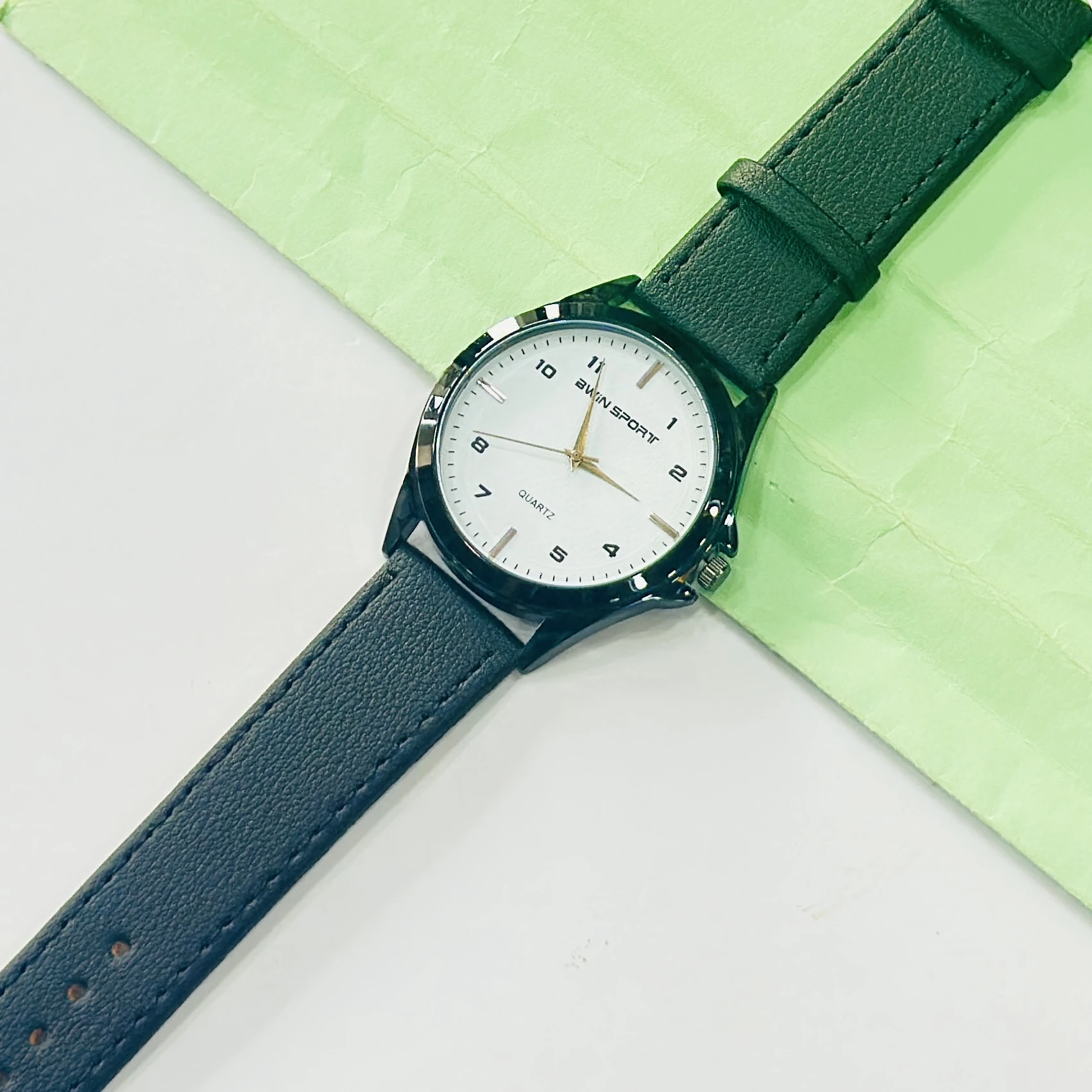 analog watch featuring a white dial, black strap, and quartz movement.