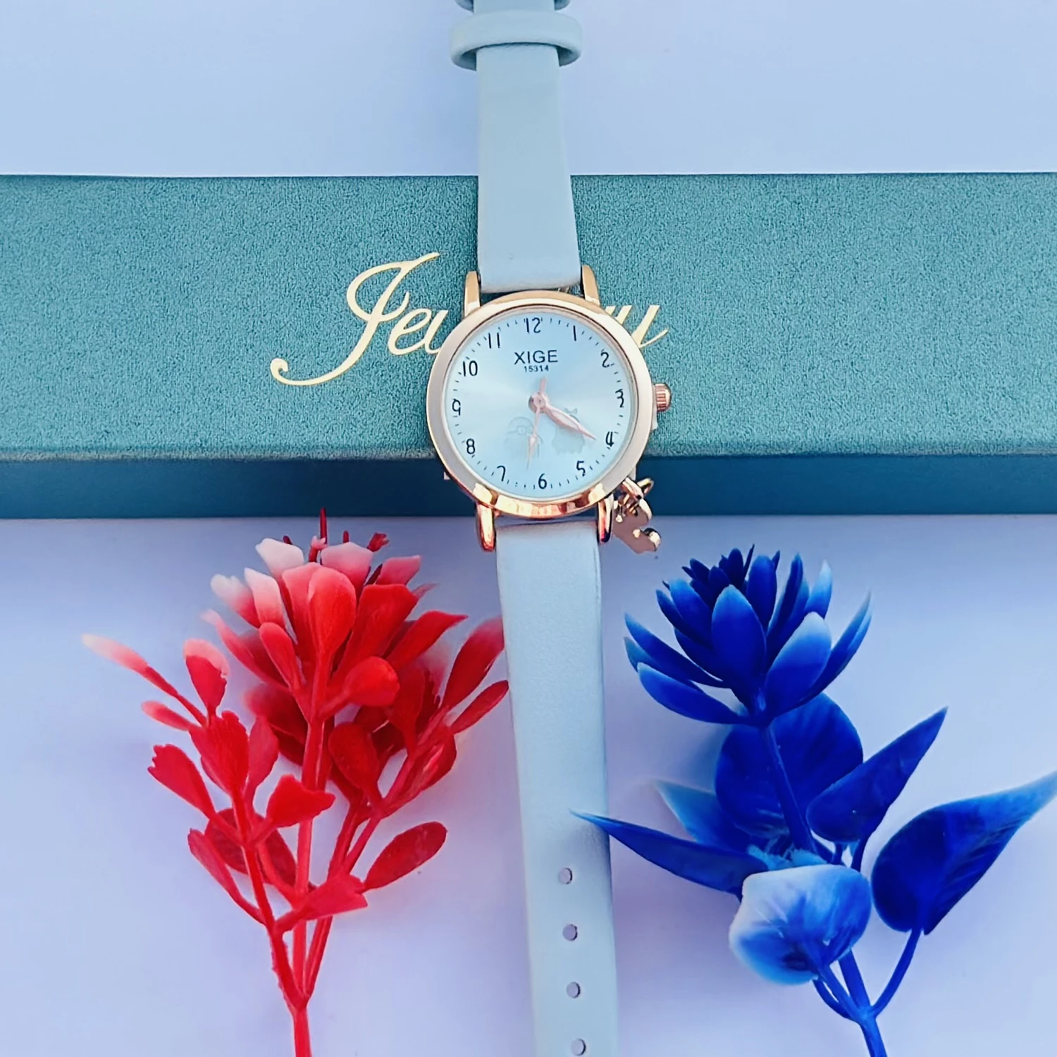 analog quartz watch with a rose gold case and a light blue leather strap featuring a horse charm.