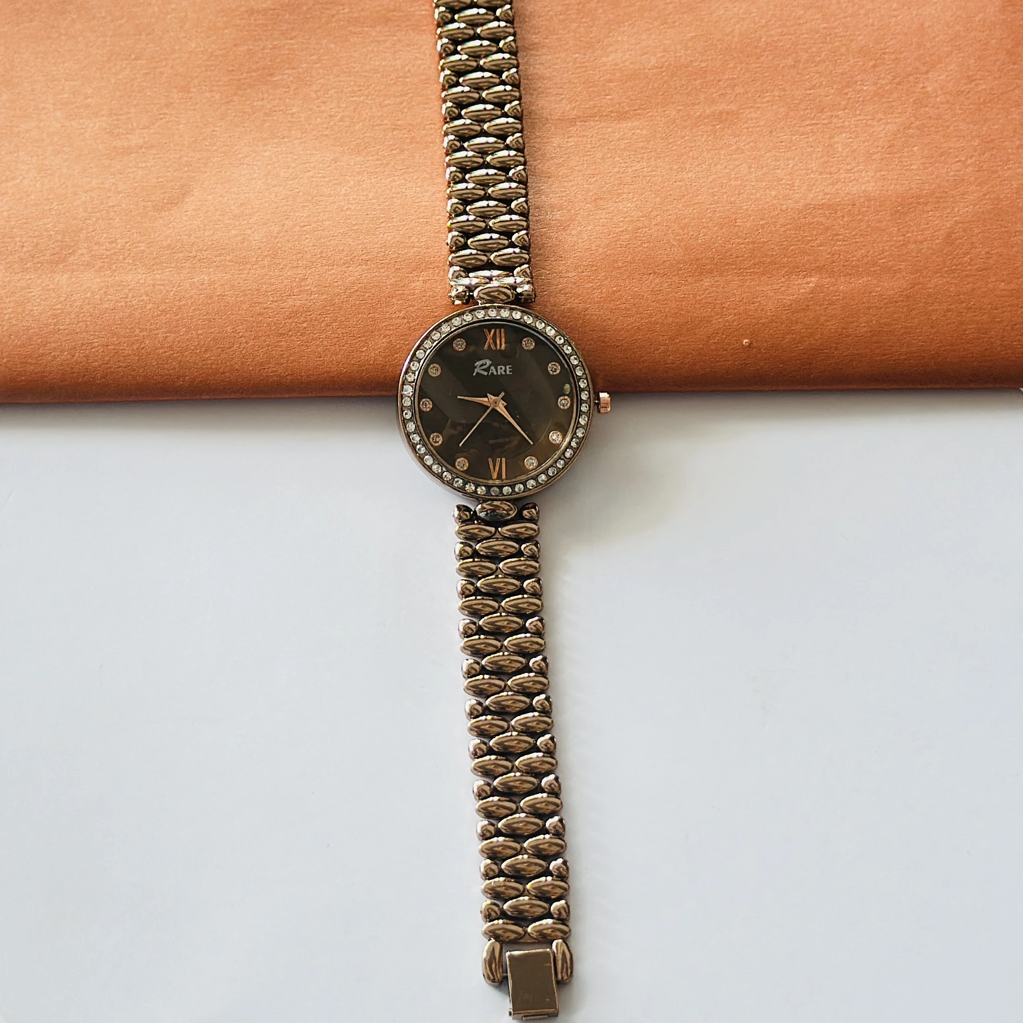 Rare analog watch with a bronze-toned metal bracelet and embellished dial.