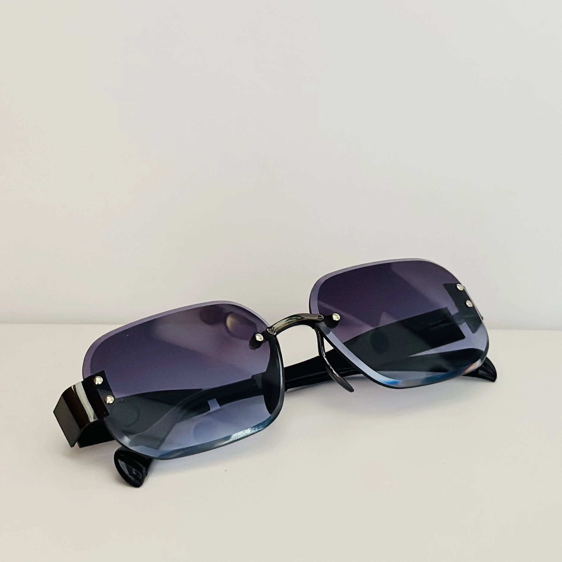 Frameless cut-edge sunglasses with black temples and a gradient tint.