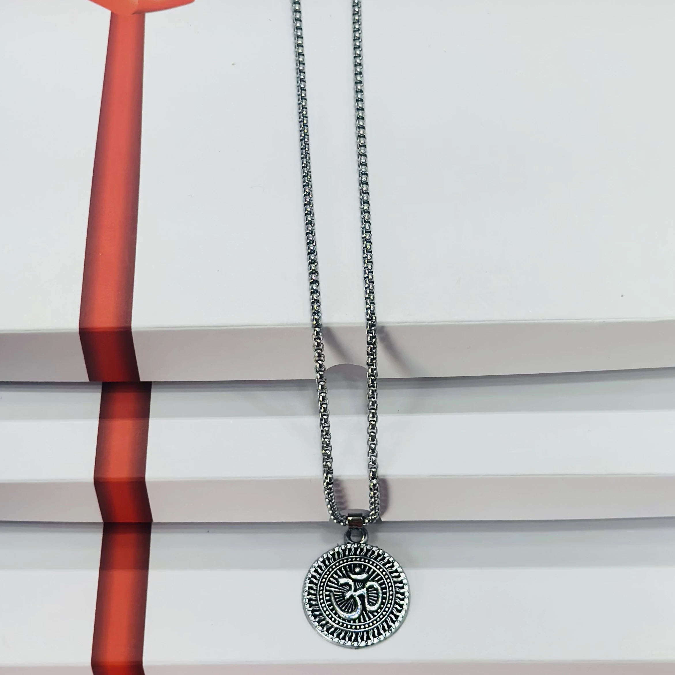 Silver toned metal necklace featuring an Om symbol pendant.