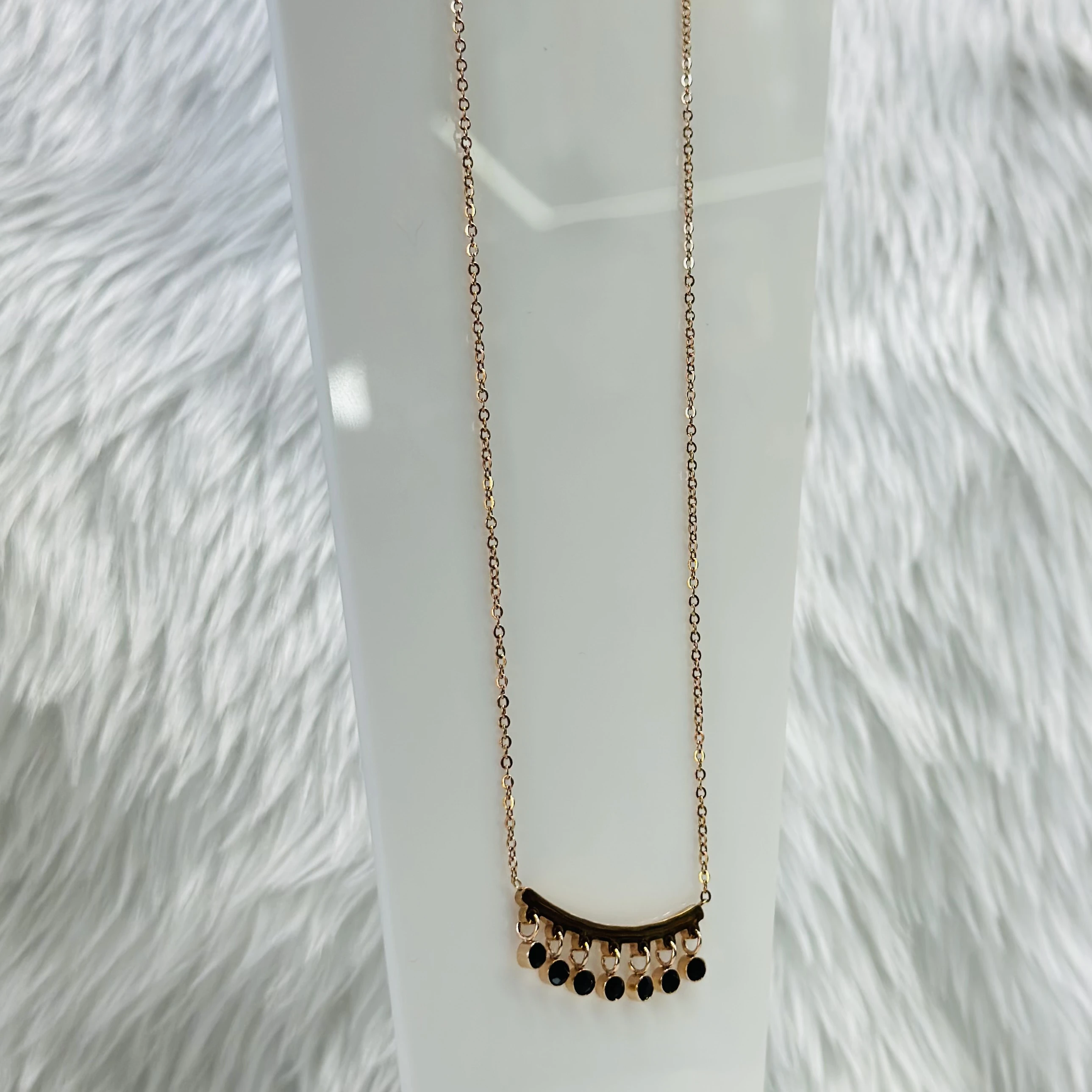 Mangalsutra necklace with a curved bar pendant and black beads.