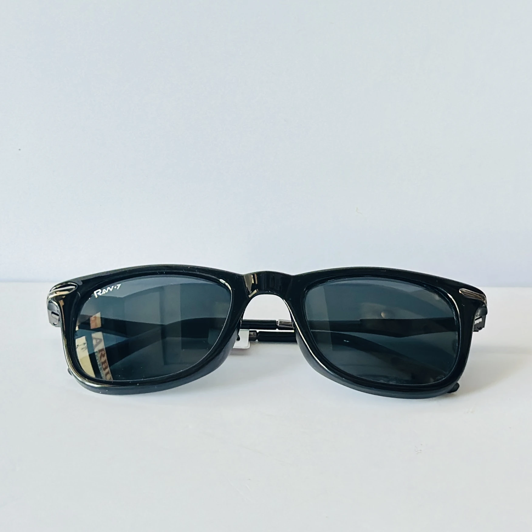 Black sunglasses appear to be similar to the iconic Ray-Ban Original Wayfarer.