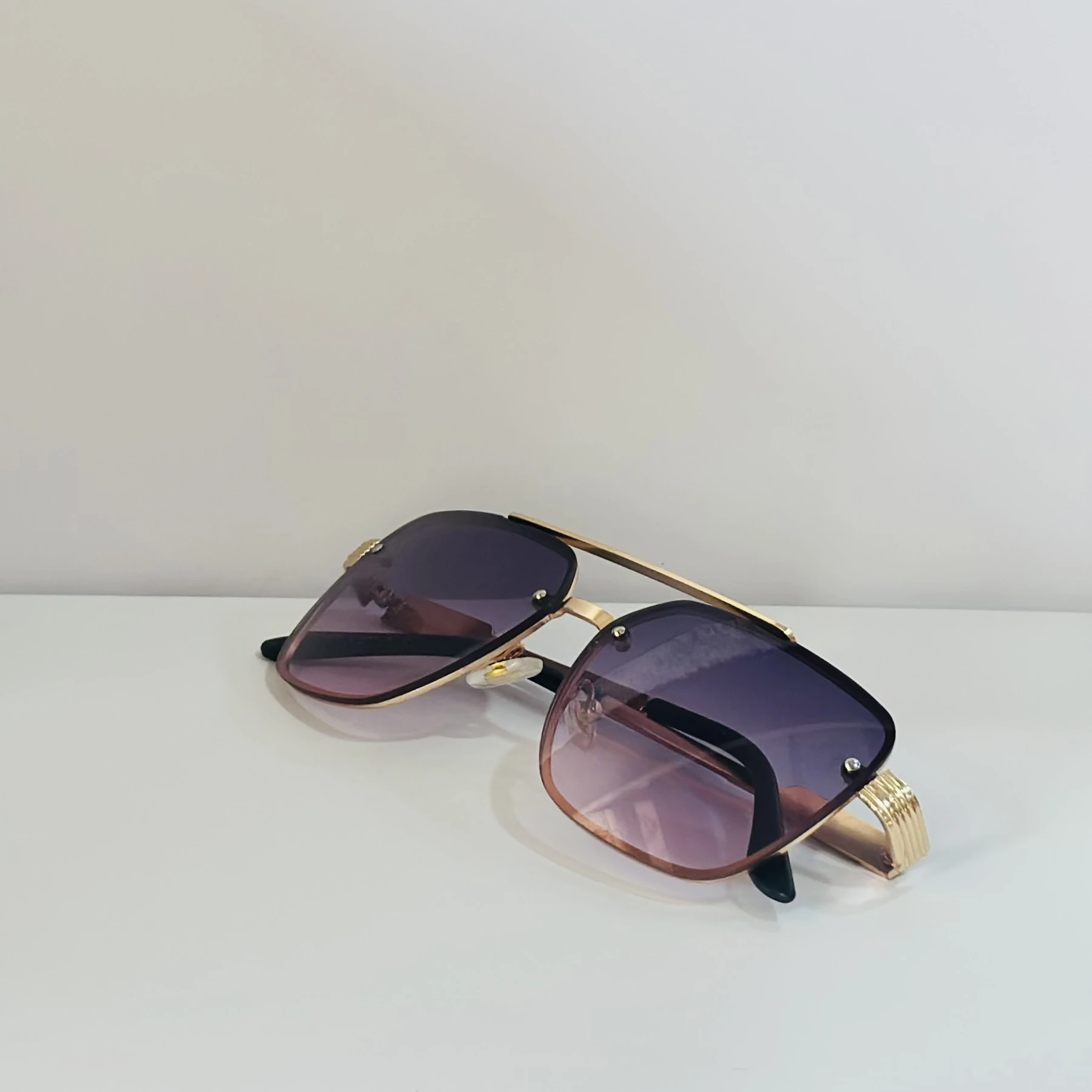 pair of fashionable sunglasses with a gold frame and purple gradient lenses.