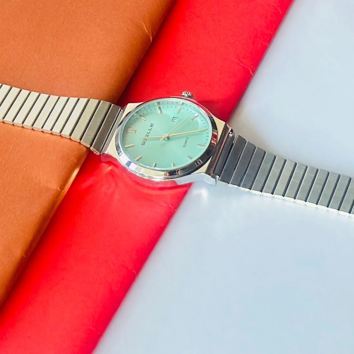 SNILLE Premium Quartz analog watch with a sky blue dial and a metal strap.