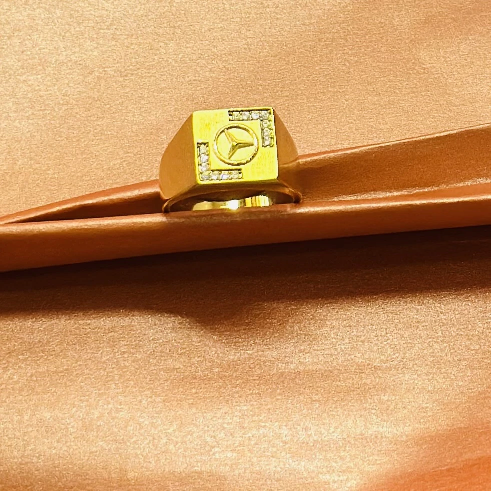 Gold plated men's finger ring with a Mercedes-Benz logo and diamond accents