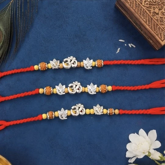 rakhis feature silver-colored "Om" and "Ganesha" symbols on red thread.