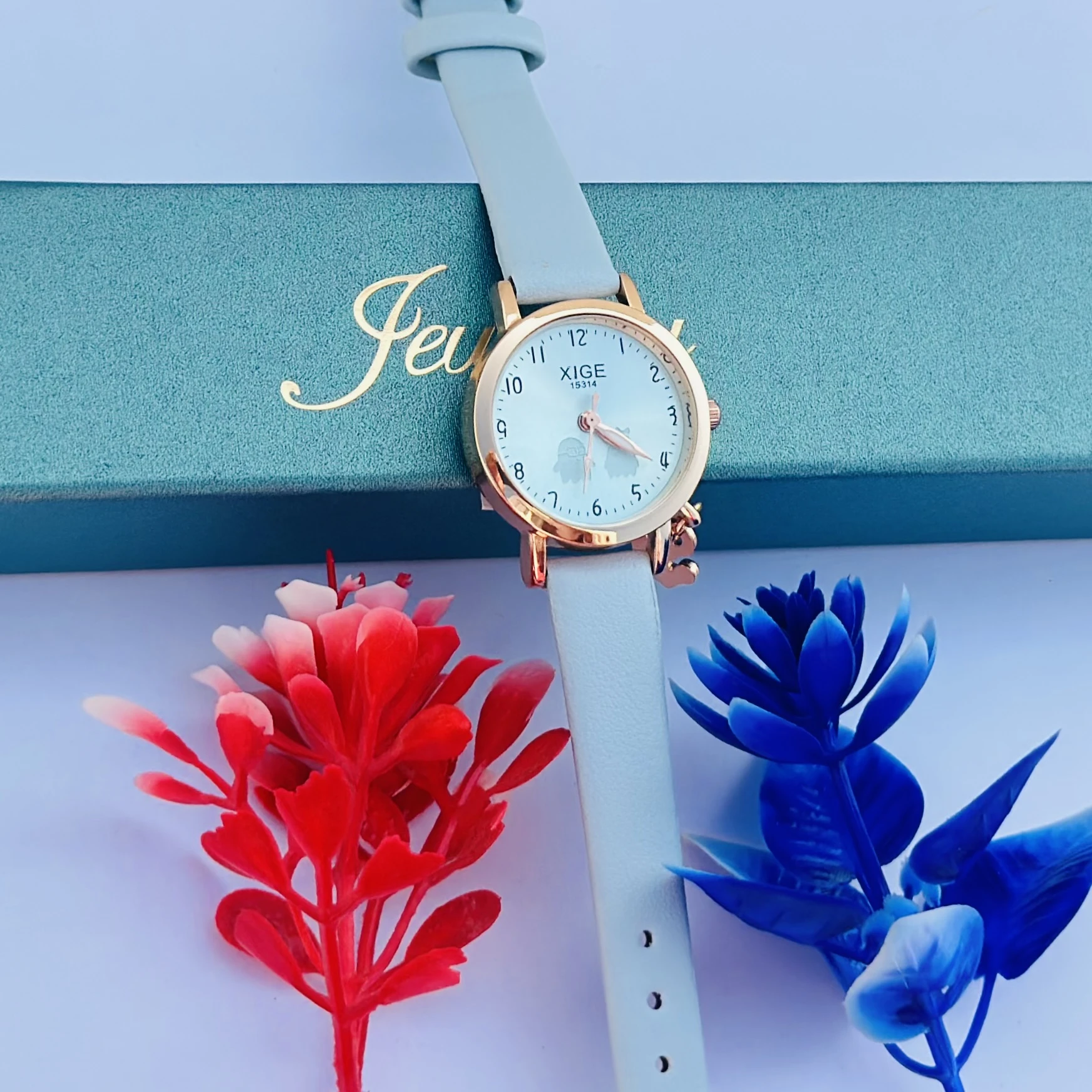 analog quartz watch with a rose gold case and a light blue leather strap featuring a horse charm.