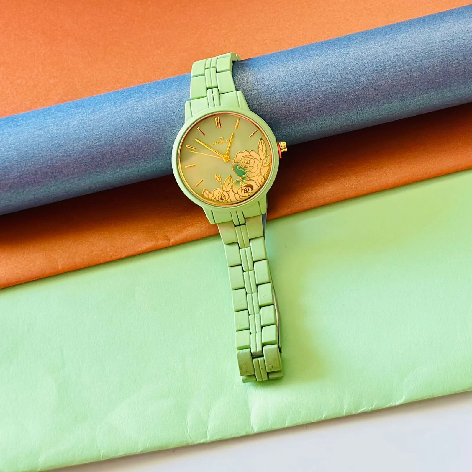 light green women's analog watch with a floral print on the dial and a link bracelet.